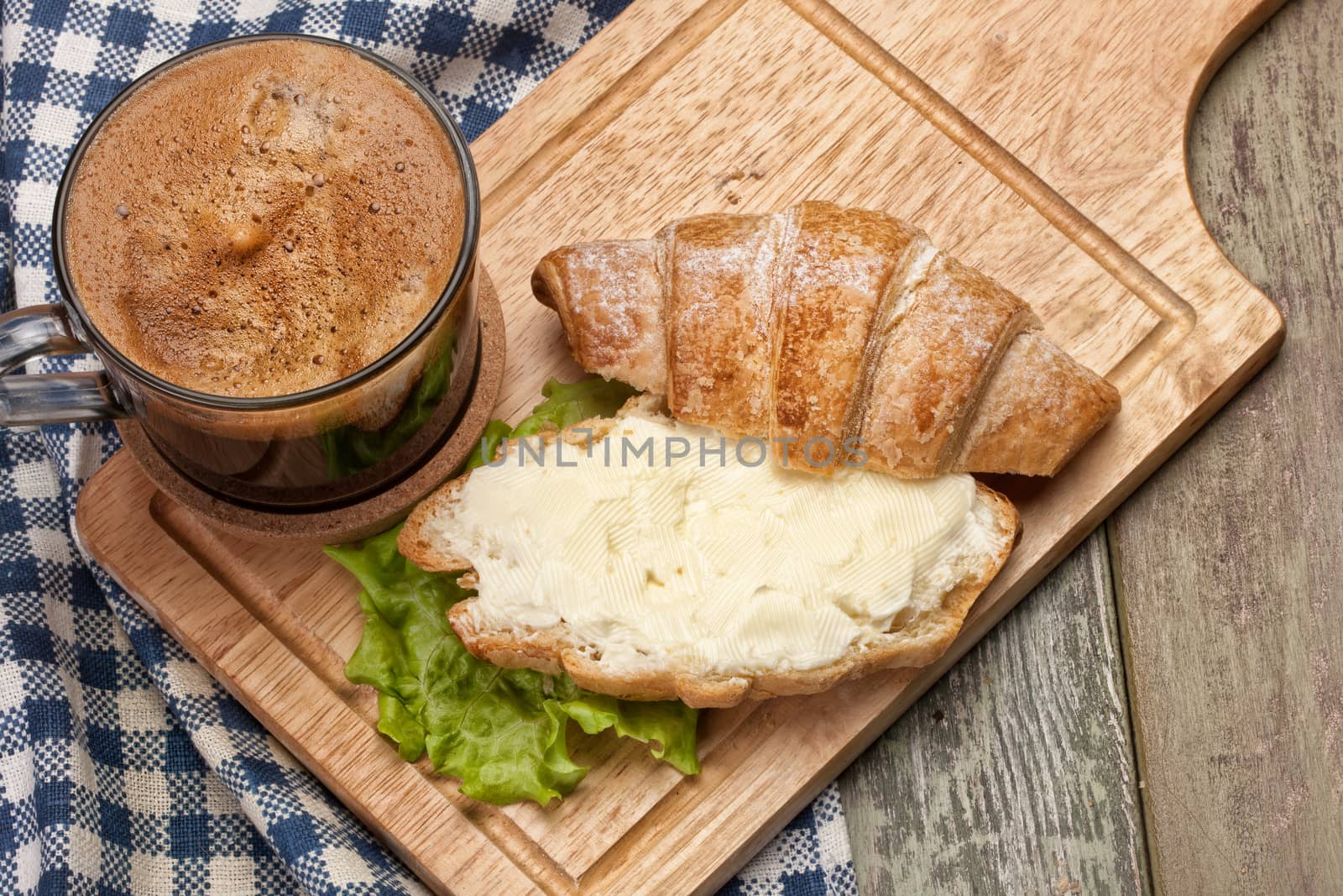 Bread, butter, coffee and greenery on a studio canvas background