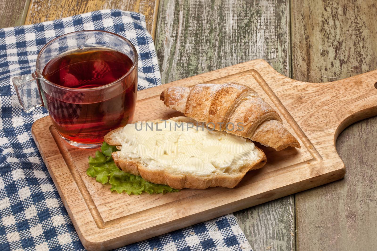 Cup of tea, bread and butter on a wooden table