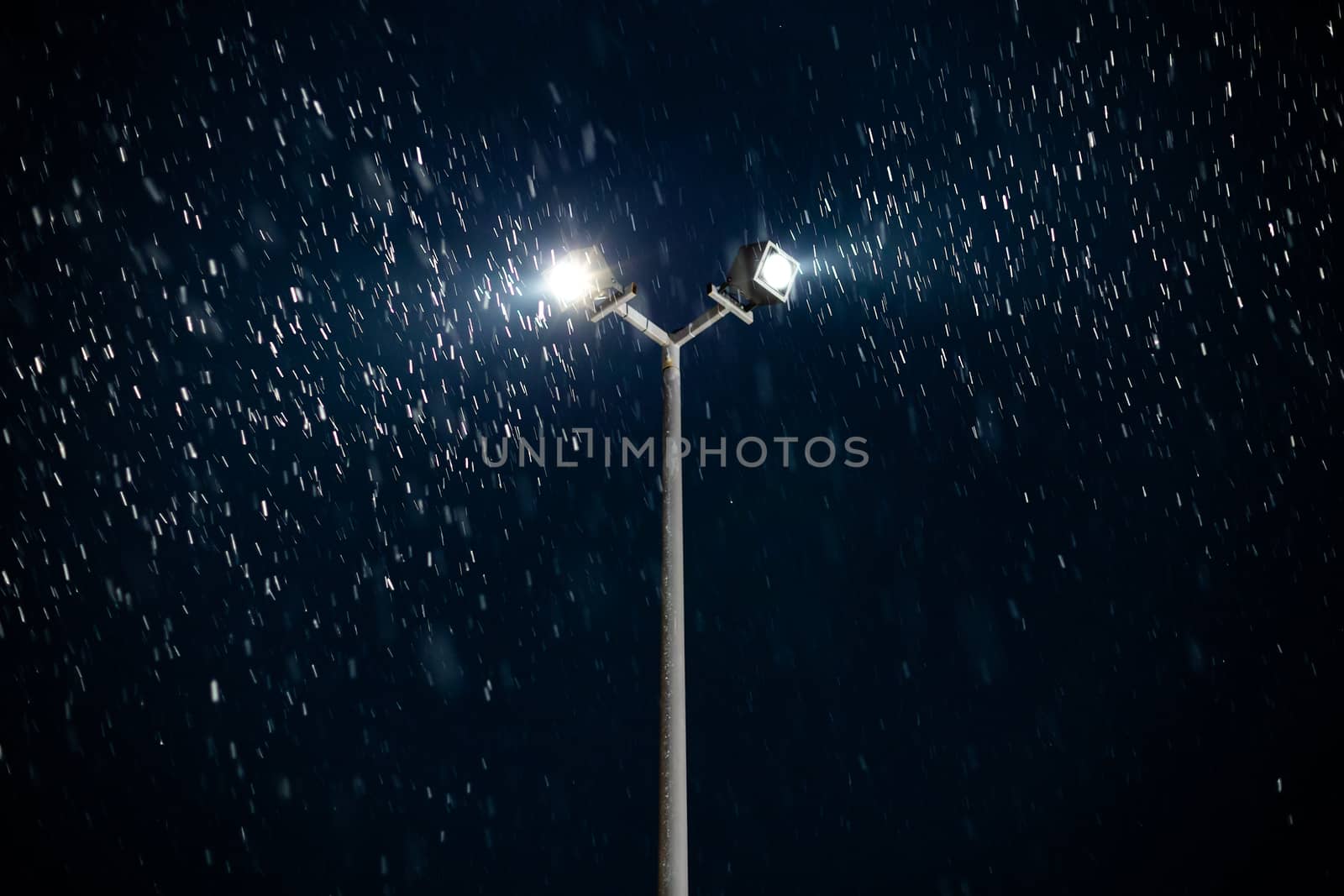 modern double light spot on lamp post at winter night snowfall.