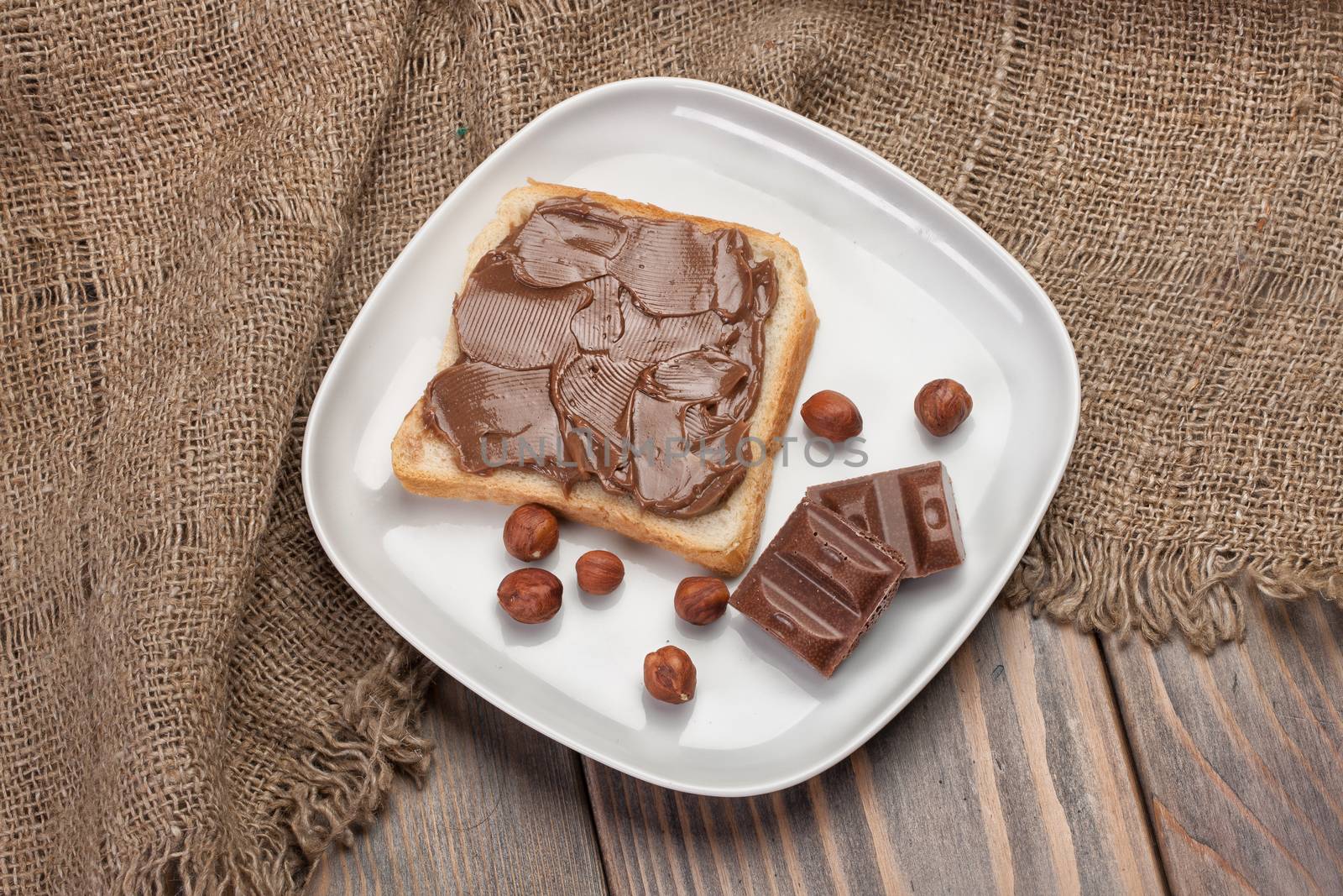 Bread, buter, chocolate and nuts on a canvas tablecloth