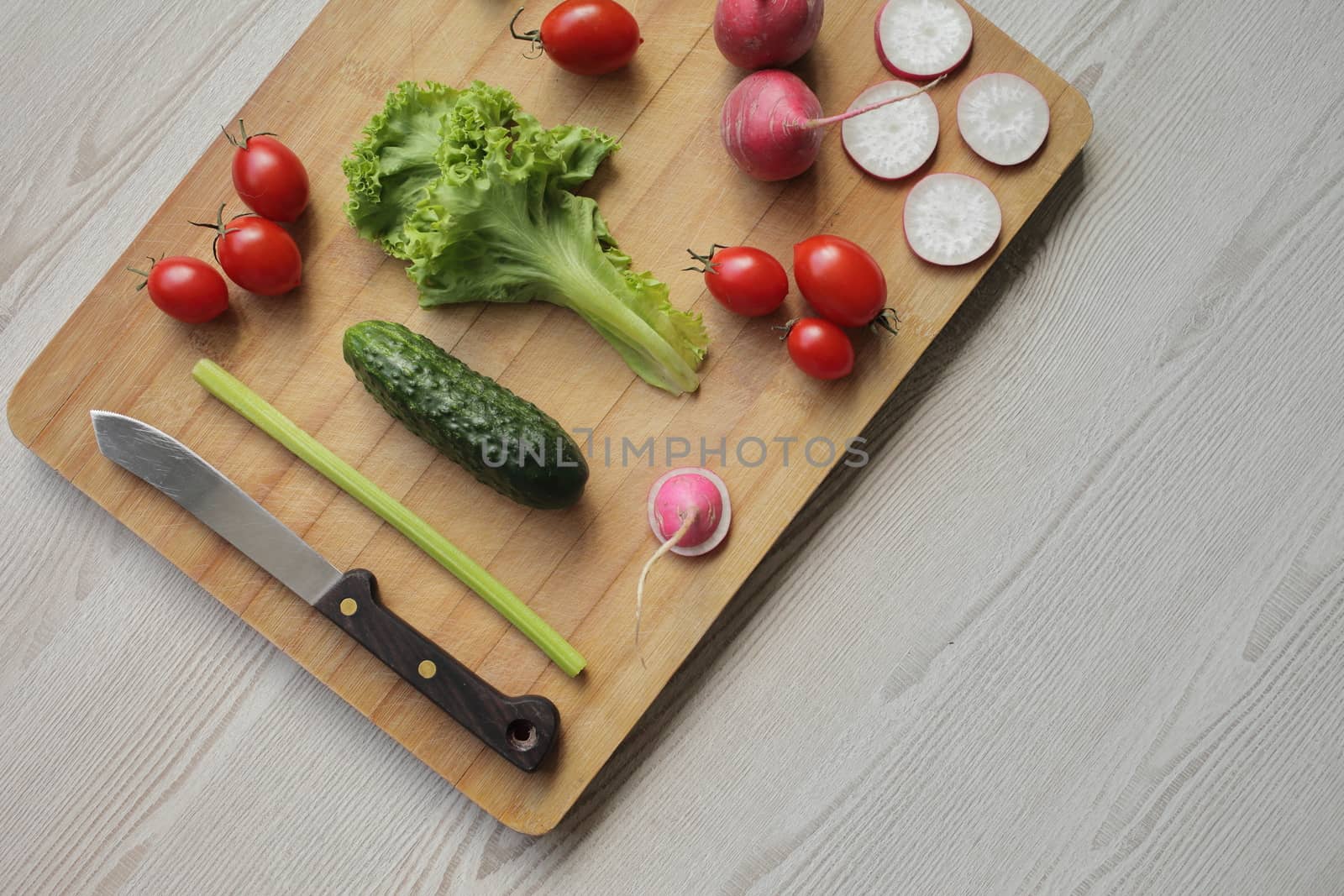Fresh vegetables on a cutting board on a light wooden table by selinsmo