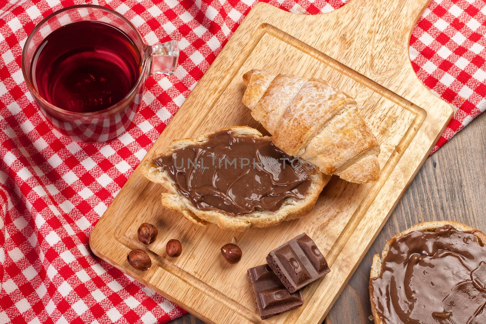 Cup of coffee, bread, butter and nuts on a wooden table