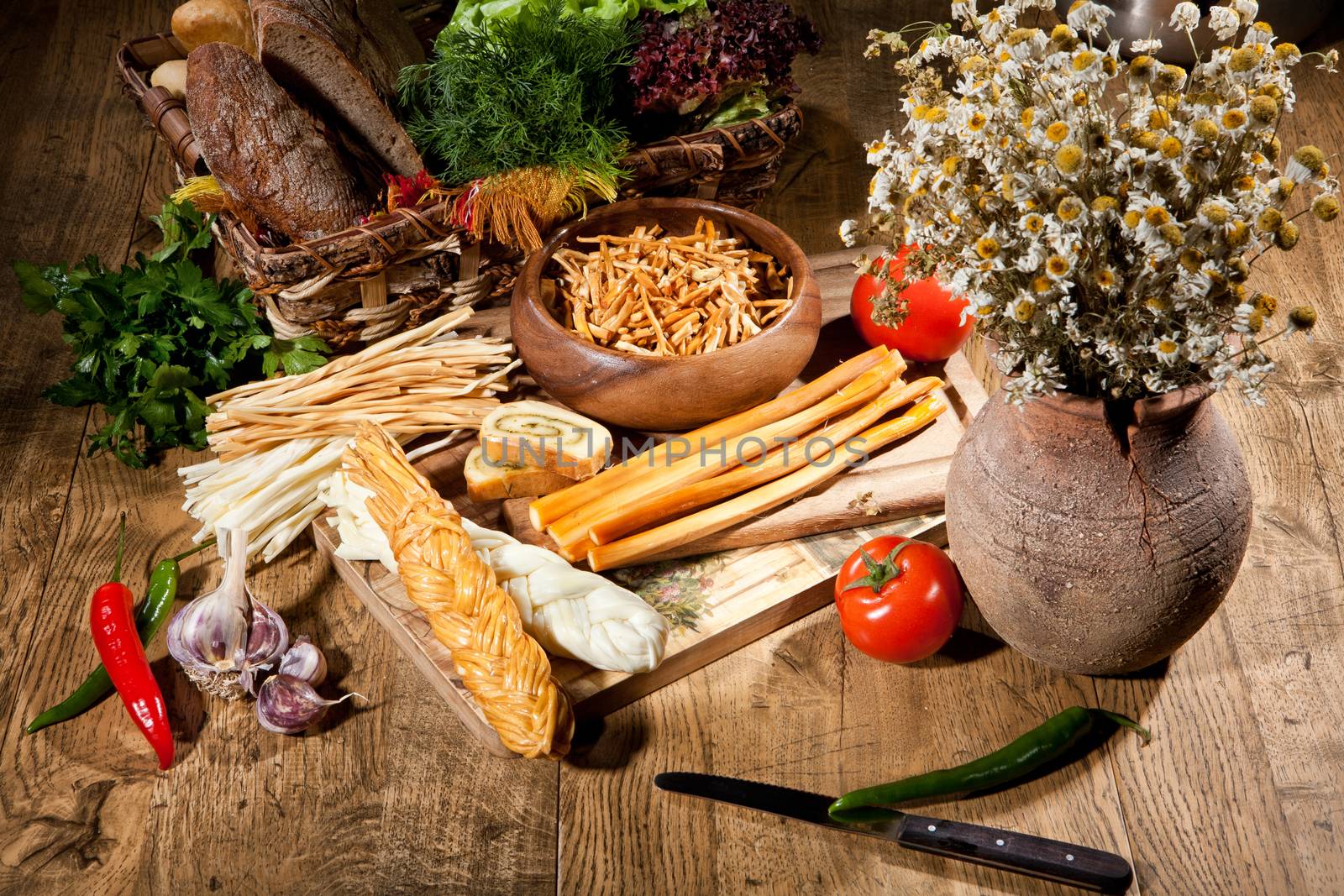 Cheese, camomiles and vegetables on an old wooden table