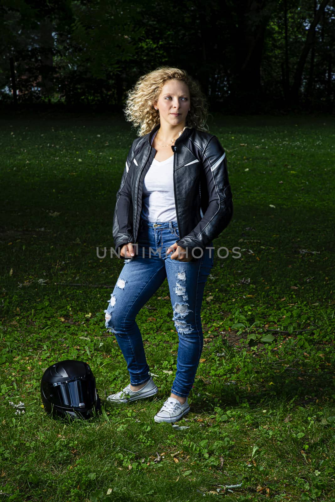 twenty something woman, wearing motocyle clothes, in a park