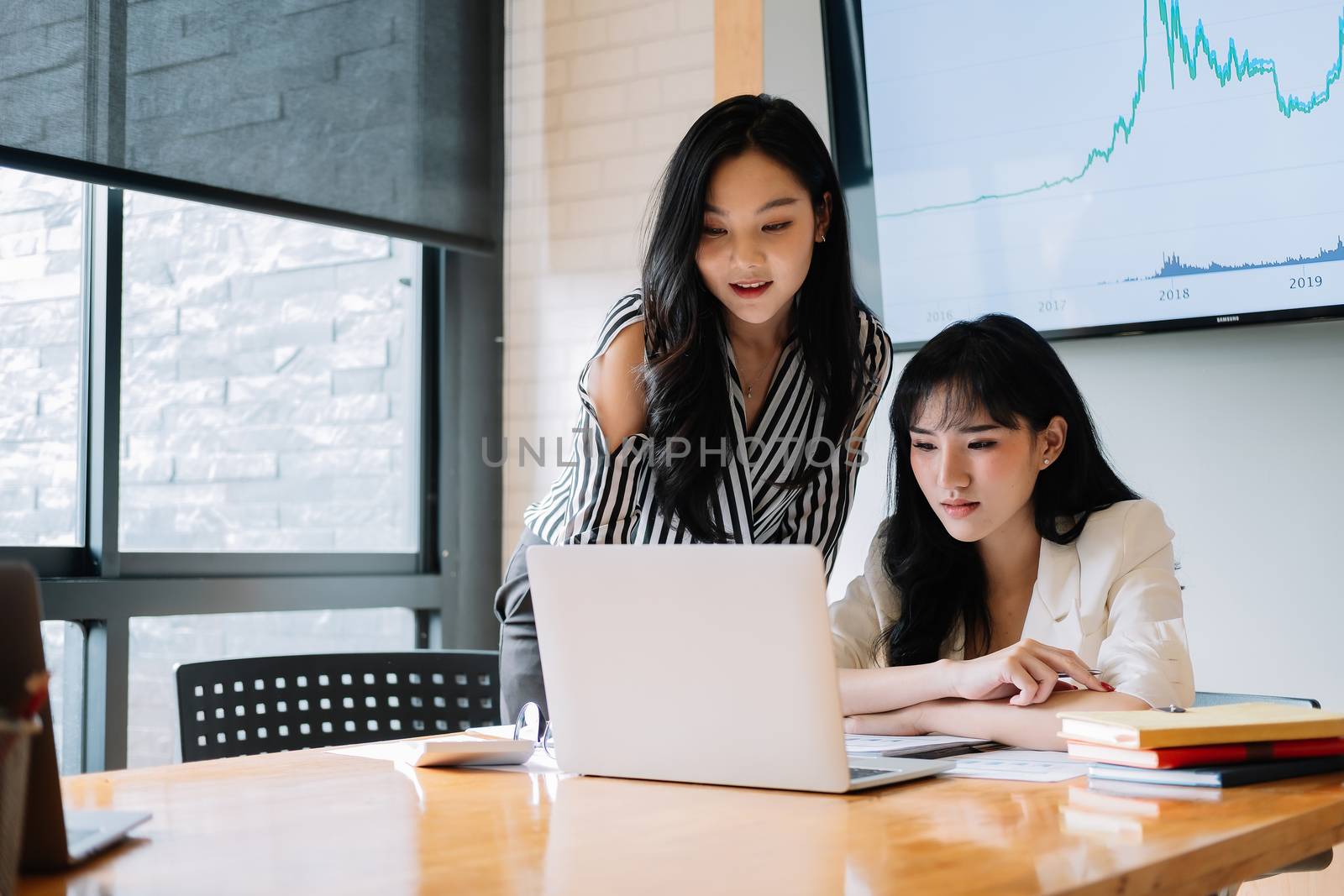Two young asia business woman working together in modern office by nateemee