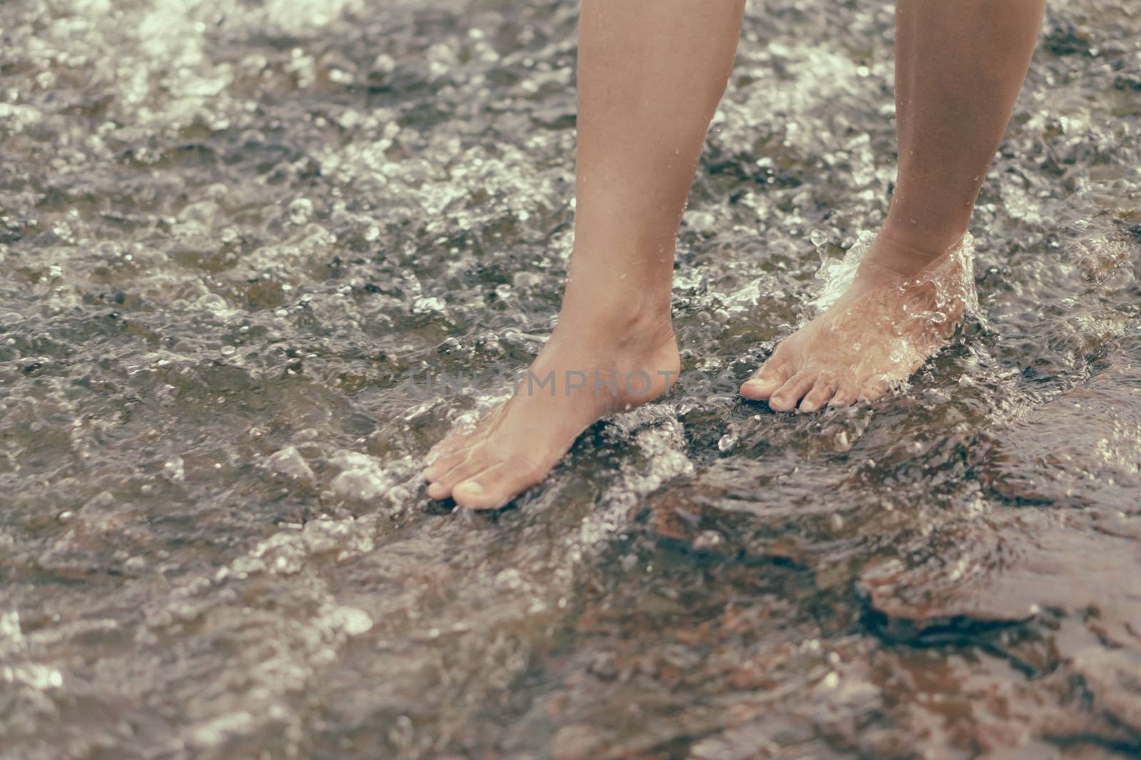 Woman legs relaxing with water on stone in the river for relax f by pt.pongsak@gmail.com