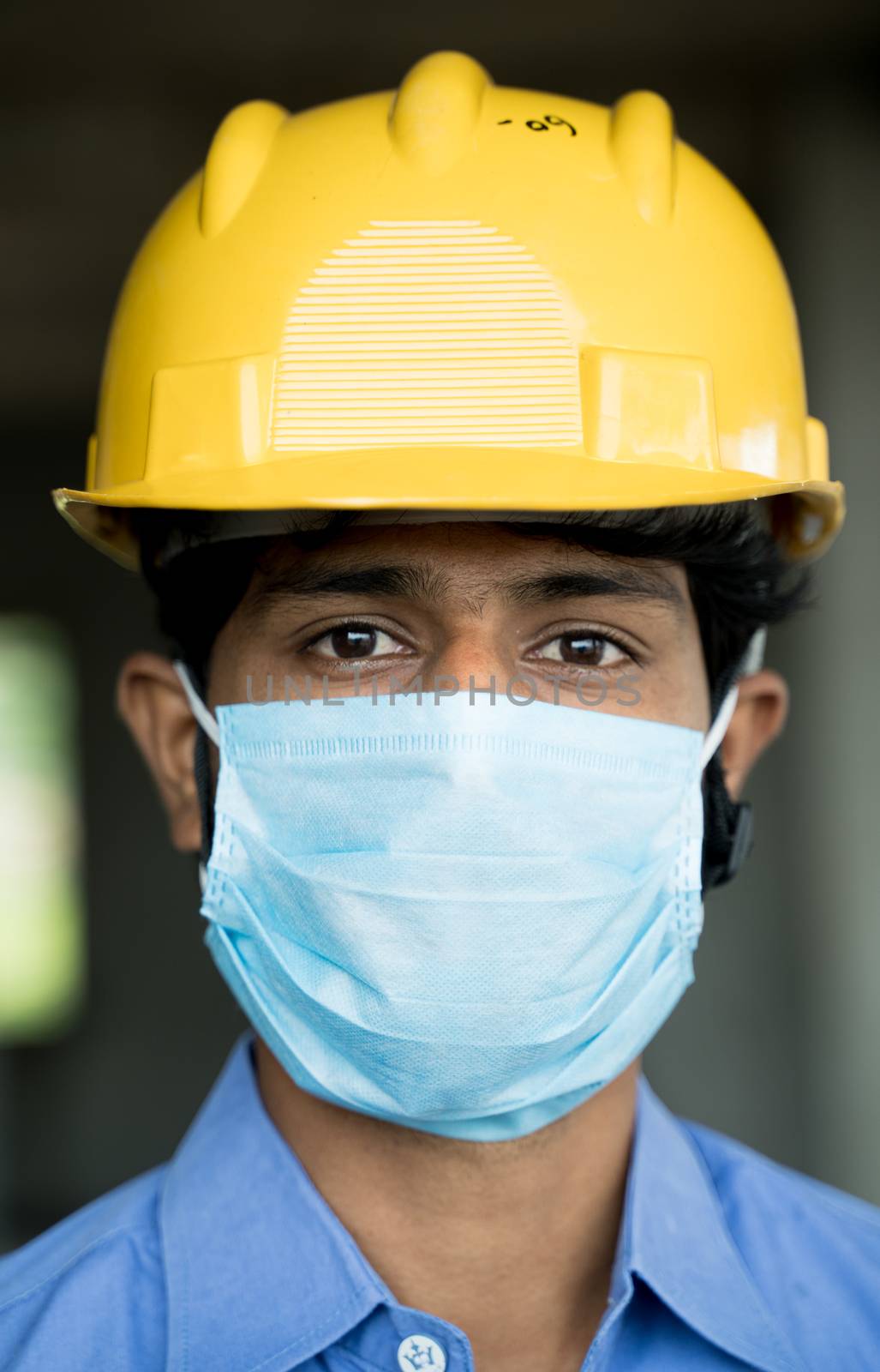 Head shot of Construction worker, reopening of construction sites or industry - construction worker in a construction helmet with medical mask due to coronavirus or covid-19 pandemic