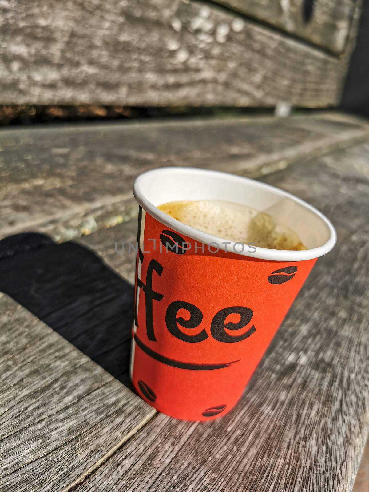 Red paper cup with coffee to go on wooden ground. Leherheide, Bremerhaven.