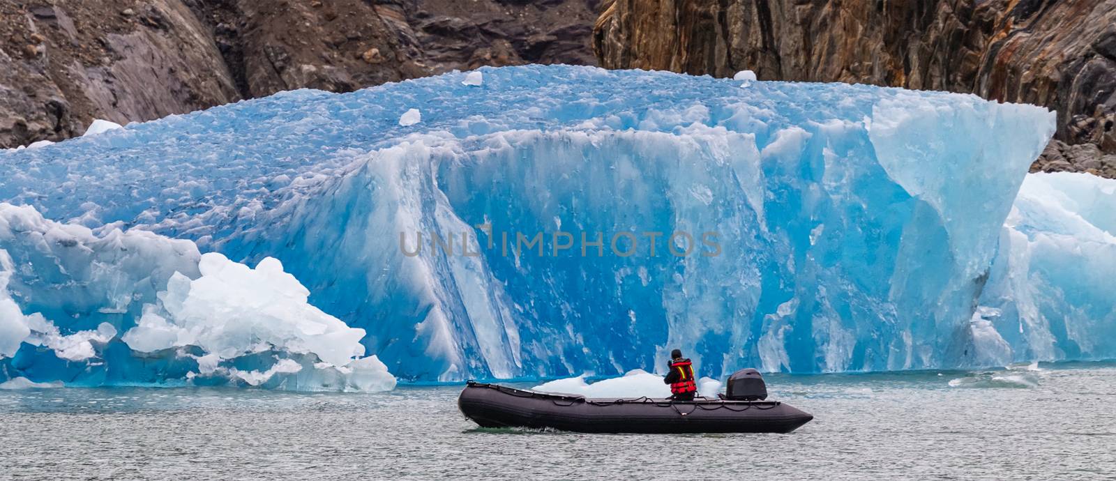 Tourist sailing in a boat by iceberg in fjord by DamantisZ