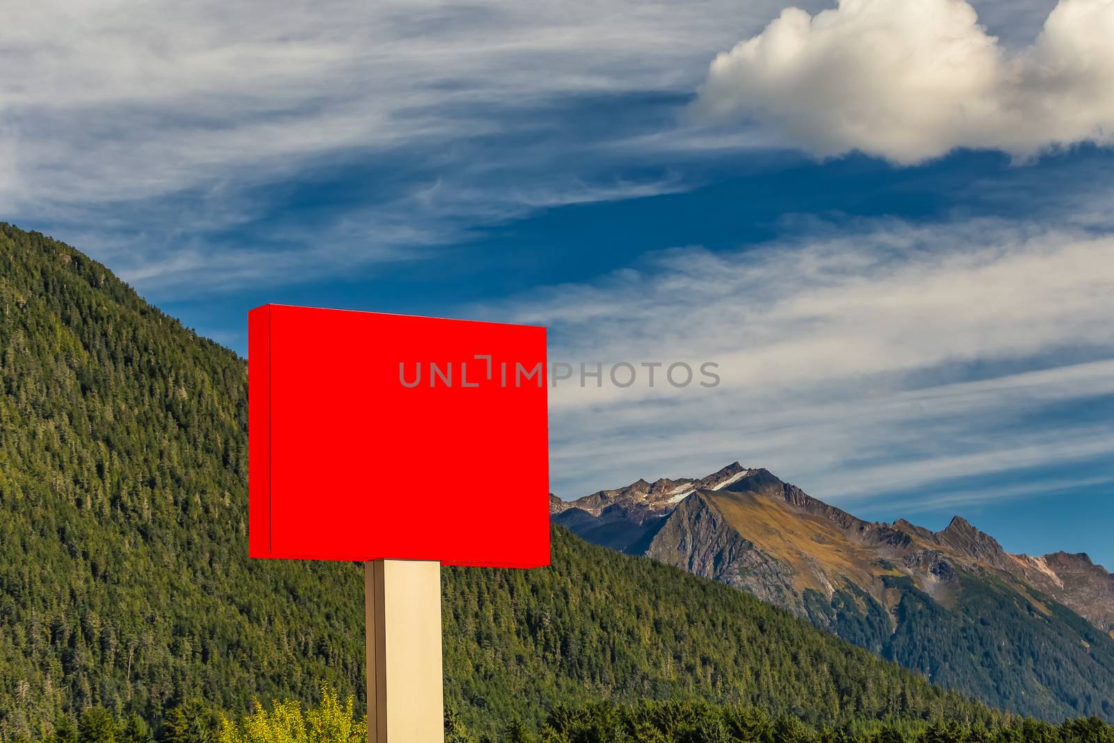 Blank red sign in the foreground and forest, mountains, blue sky with clouds in the background