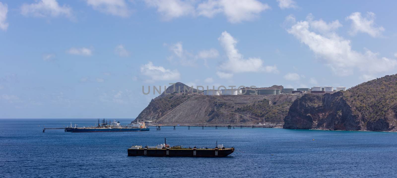 St. Eustatius island. Panorama of huge fuel tanks up on the hills and fueling barges in the front.