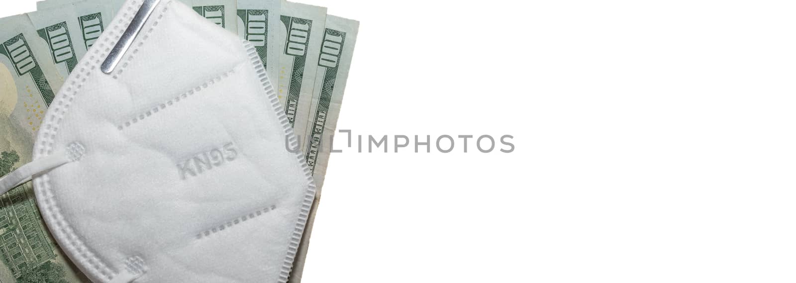 Part of facial protective mask KN95 on top of a few hundred dollar bills. Isolated. White background. Expensive protection against viruses, bacteria.