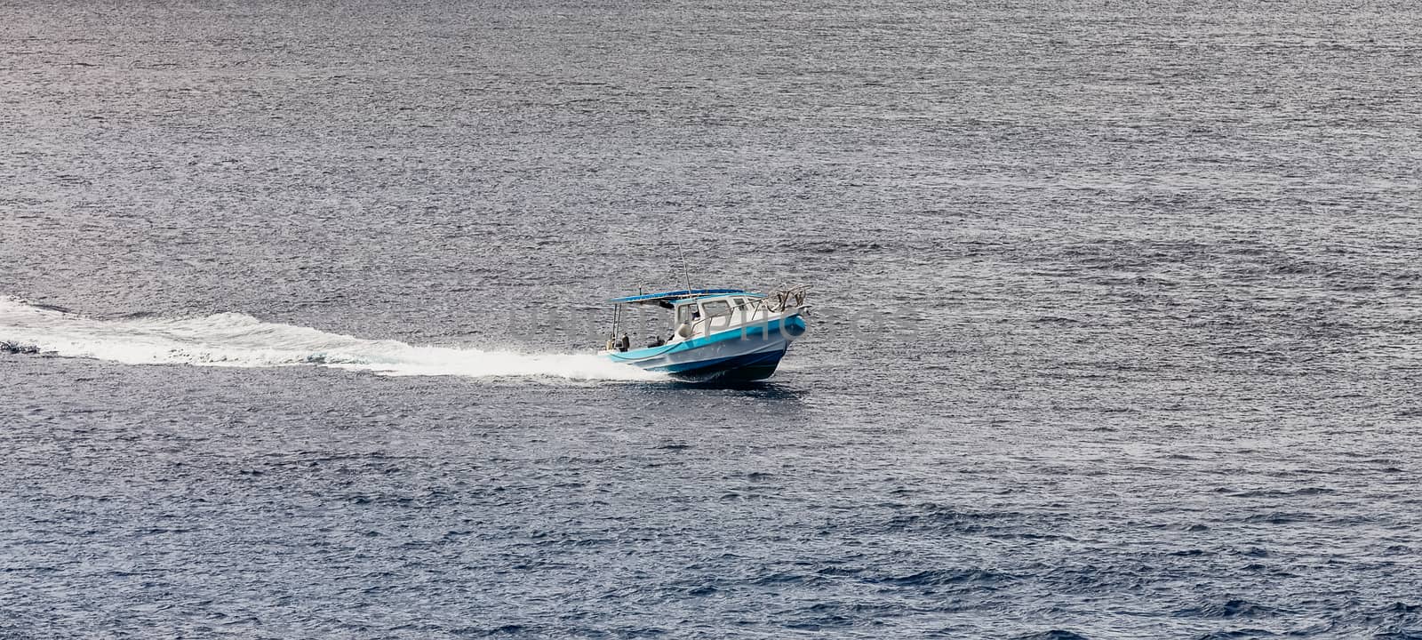 Fishing boat sailing by the island of Cozumel in Mexico. Stormy weather, clouds and rain in the background.