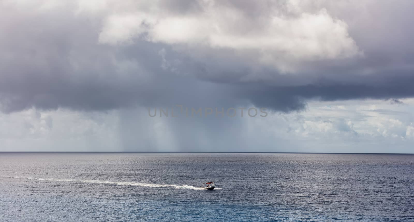 Fishing boat sailing by the island of Cozumel in Mexico. Stormy weather, clouds and rain in the background