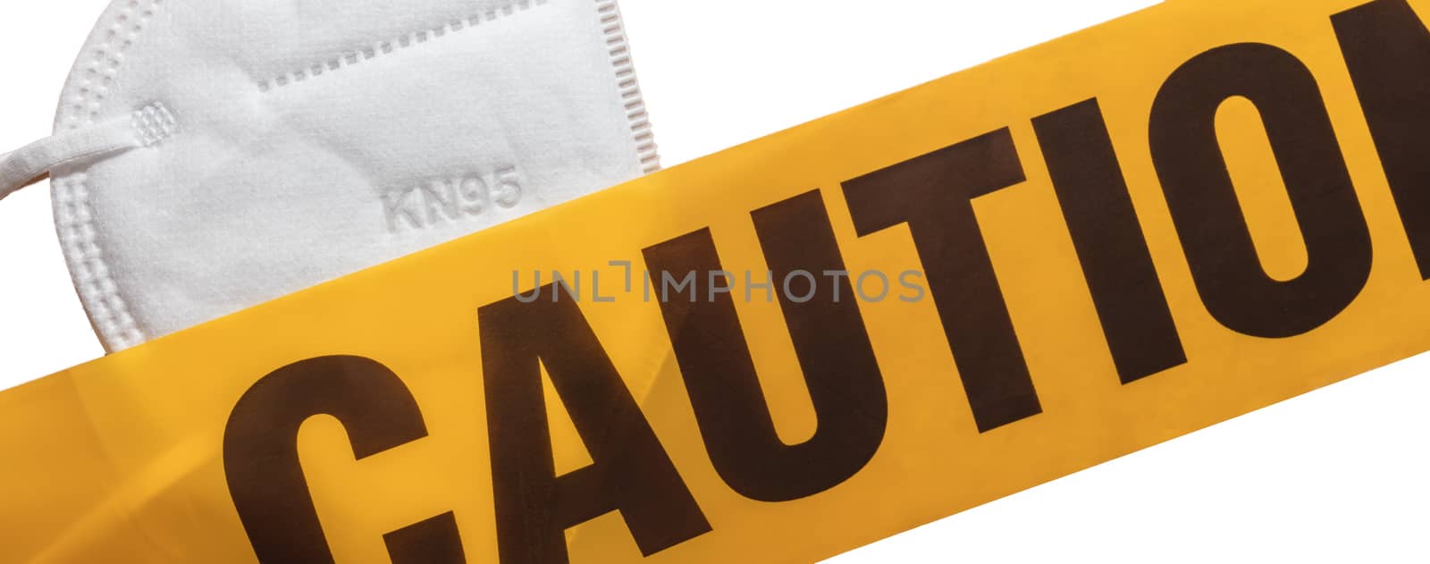 Facial protective mask KN95 covered by yellow caution tape. Isolated. White background. Protection against viruses, bacteria, germs. PPE. Quarantine.