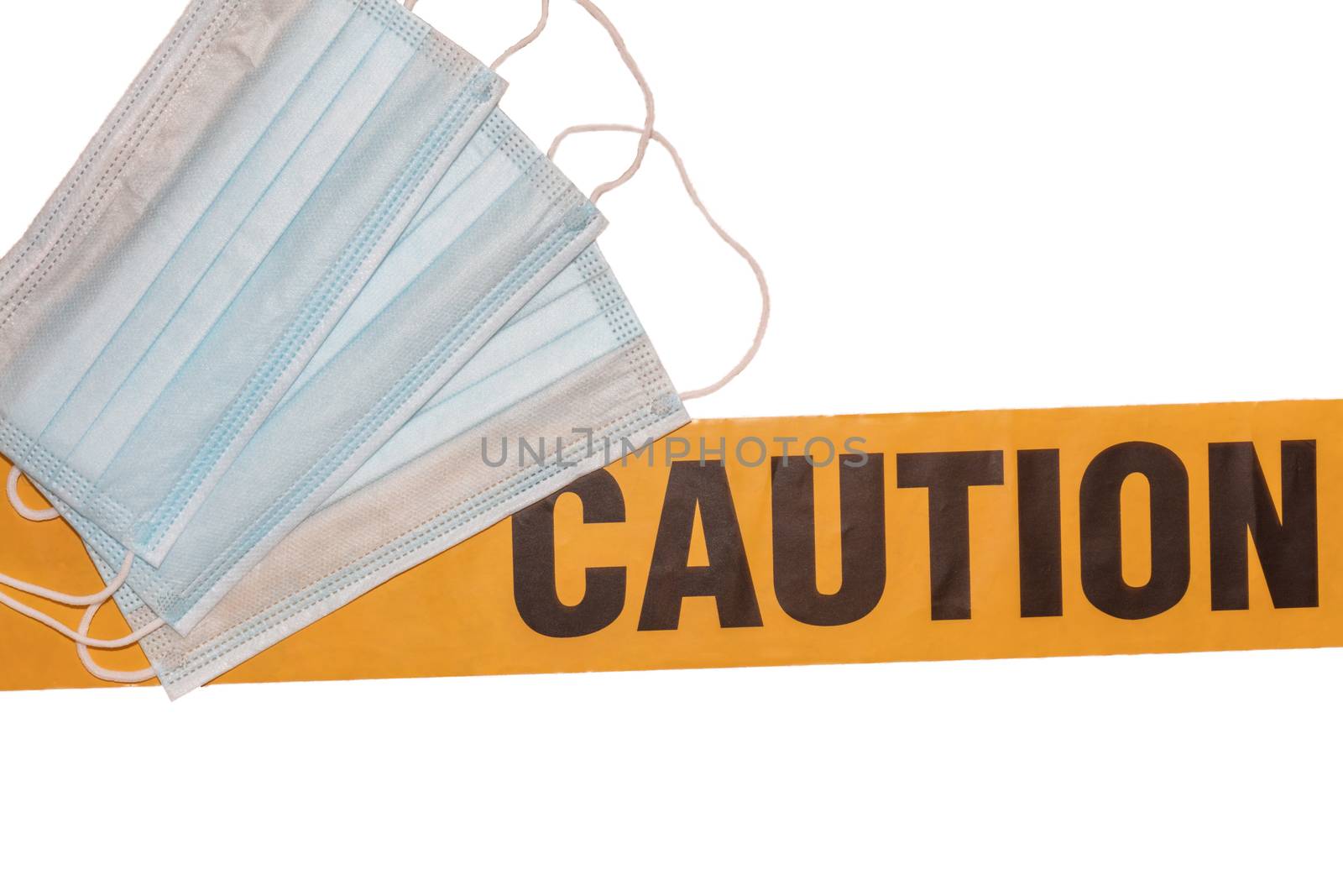 Facial protective masks on top of yellow caution tape. Isolated. White background. Protection against viruses and bacteria. PPE. Quarantine area.