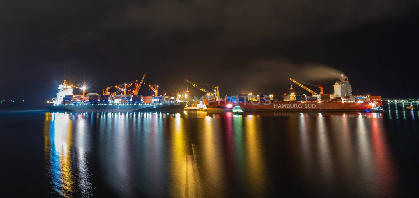 Papeete, French Polynesia - October 2, 2018: Night shot. Papeete port with loading cranes and cargo ships being loaded with containers. Beautiful lights. Long exposure.