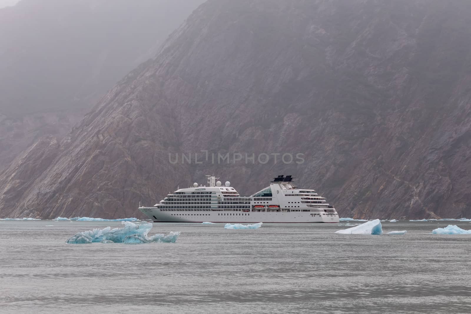 Tracy Arm Fjord, Alaska, US - August 23, 2018: Seabourn Sojourn sailing among icebergs with a mountain behind it in Tracy Arm Fjord in Alaska, USA