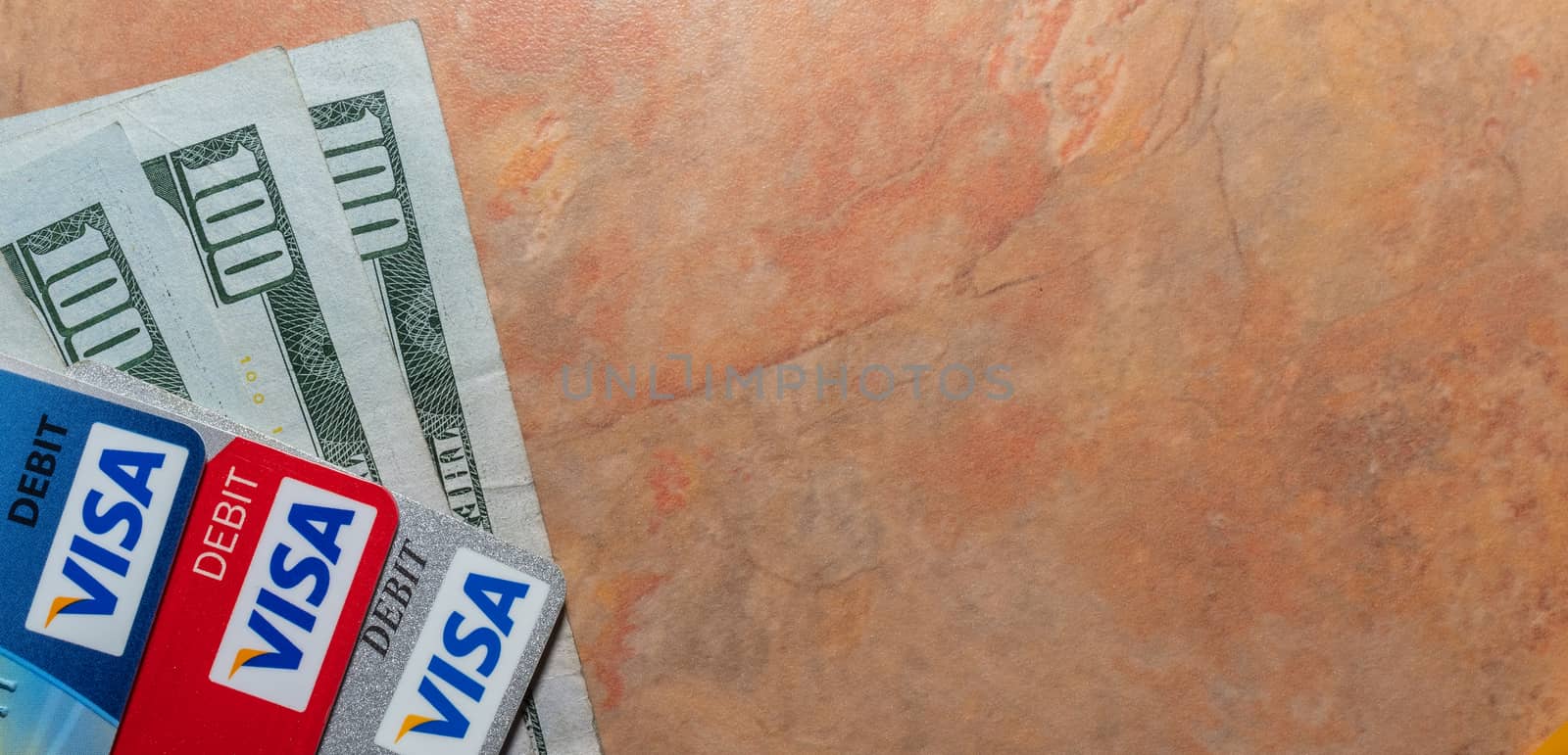 Miami, Florida - May 29, 2020: Hundred dollar bills and visa debit cards on top of them. Marble table background. Isolated. Banking concept. Illustrative editorial.