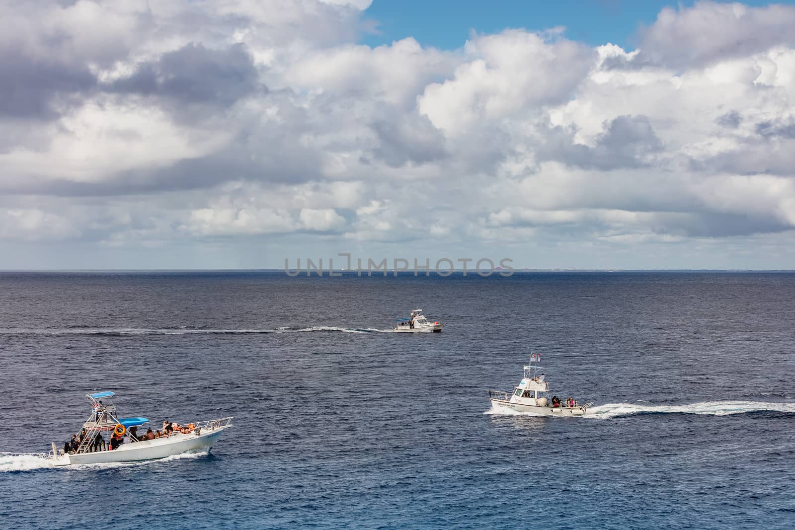 Cozumel, Mexico - December 17, 2019: Fishing and diving boats sailing by the island of Cozumel in Mexico. Boats full of tourists. Beautiful clouds in the background.