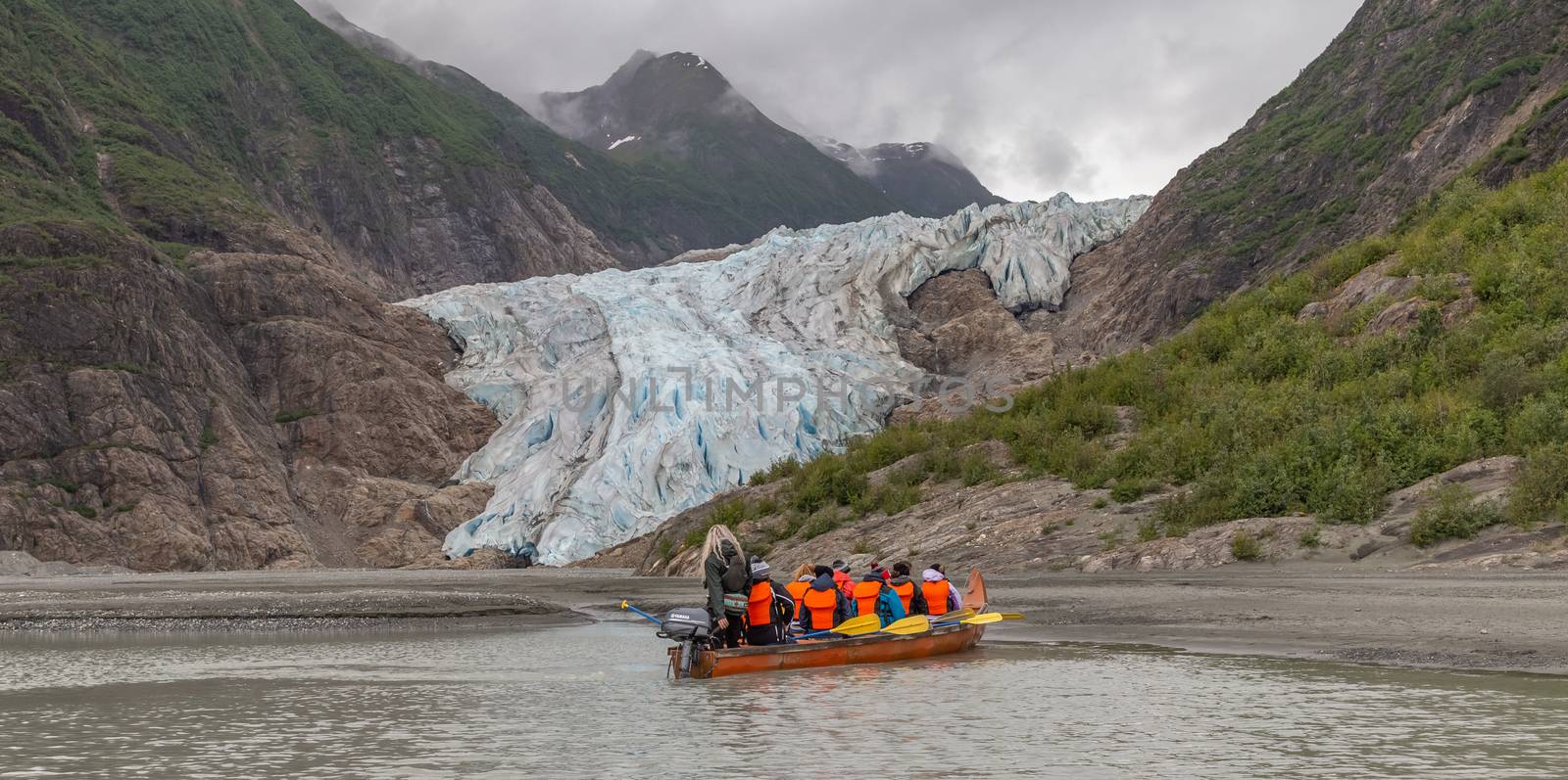 Davidson Glacier, Alaska, US - June 29, 2018: Tourists and a guide sailing in a canoe towards Davidson Glacier