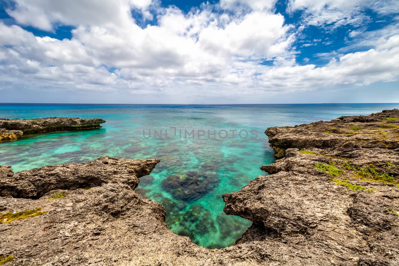 Background view of shallow turquoise waters with coral reefs underneath the surface and fringing reefs encircling it above the surface. Clear horizon