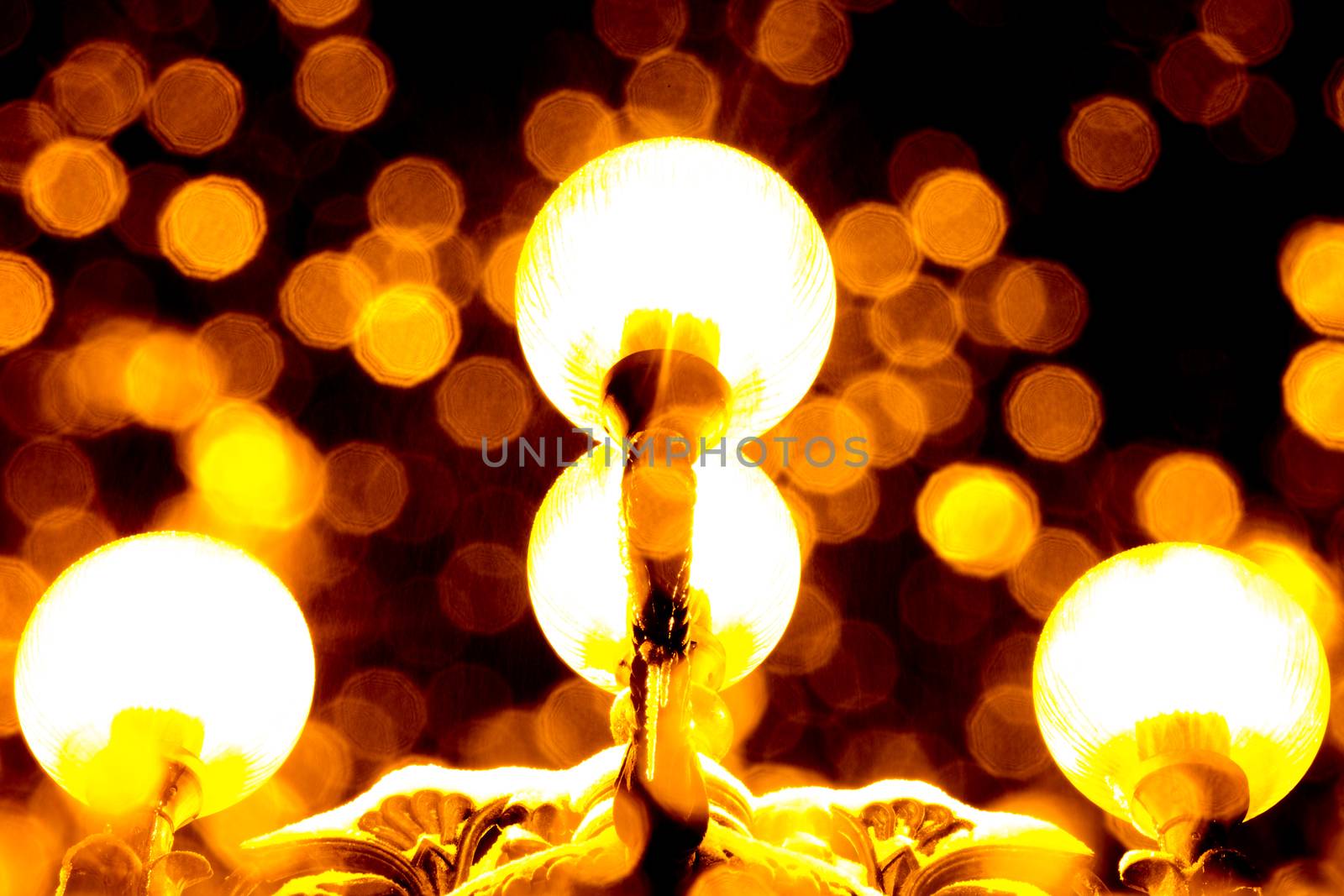 Close-up shot of antique yellow lantern at night with blurred snow flakes falling down.