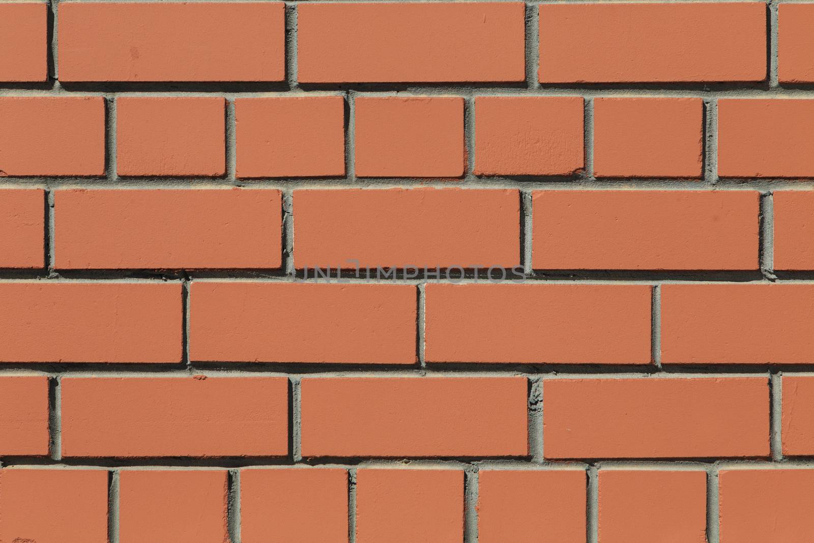 Front close-up view of a flat brick wall with brown bricks symmetrically spread out