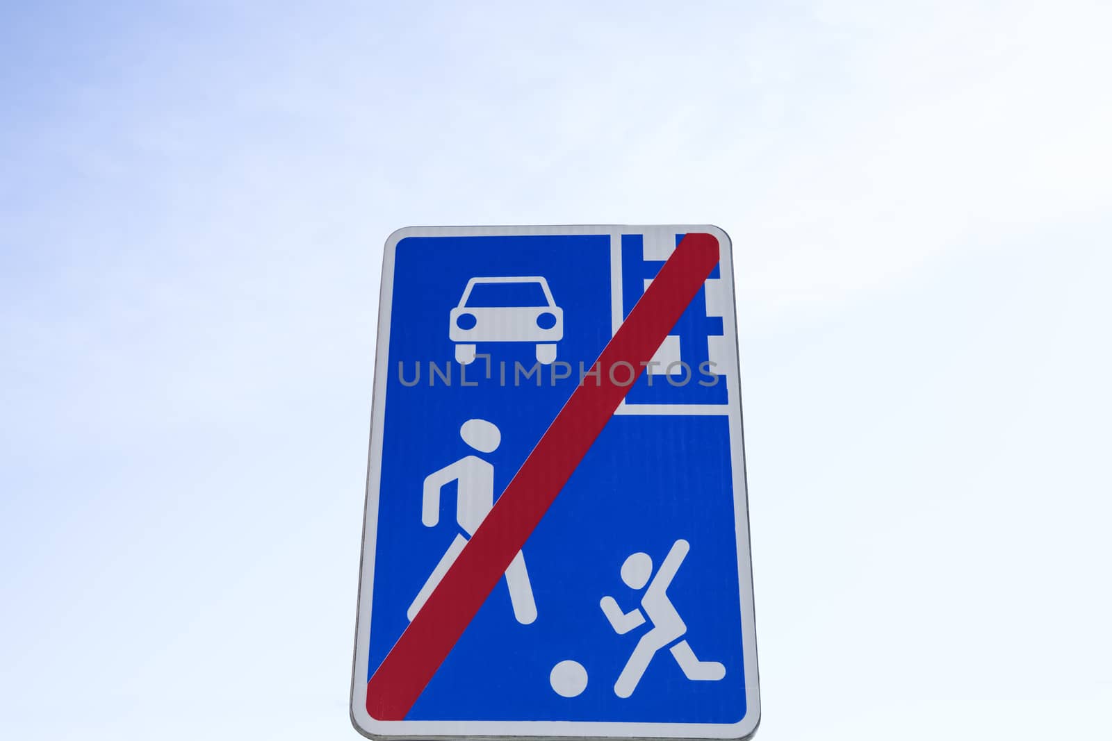 Traffic sign showing a car, a child and an adult crossed with red line. End of residential area.