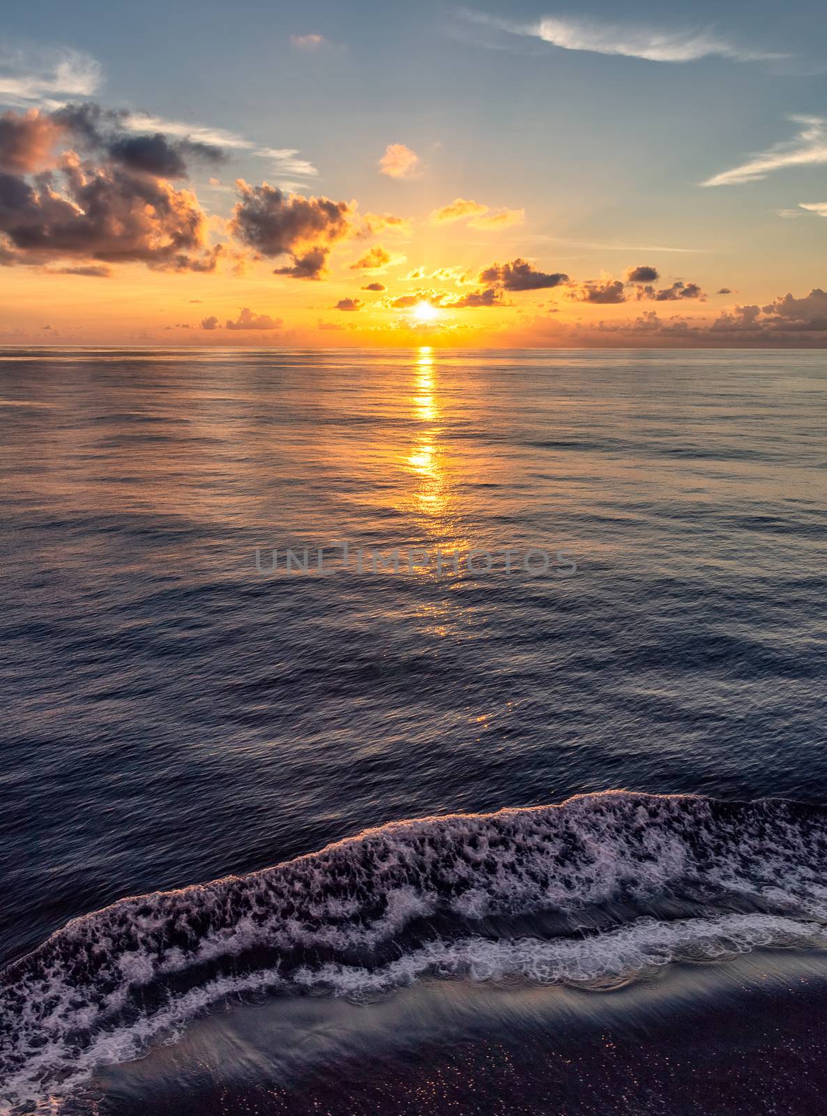 Beautiful Caribbean sunset with water splashing in the foreground and orange-and-blue sky in the background