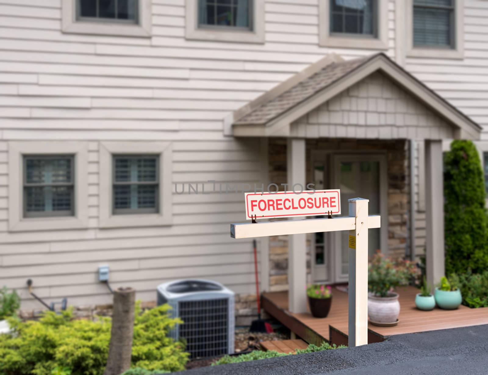 Mockup of a foreclosure sign in front of a modern townhome or townhouse to illustrate recession fears due to coronavirus