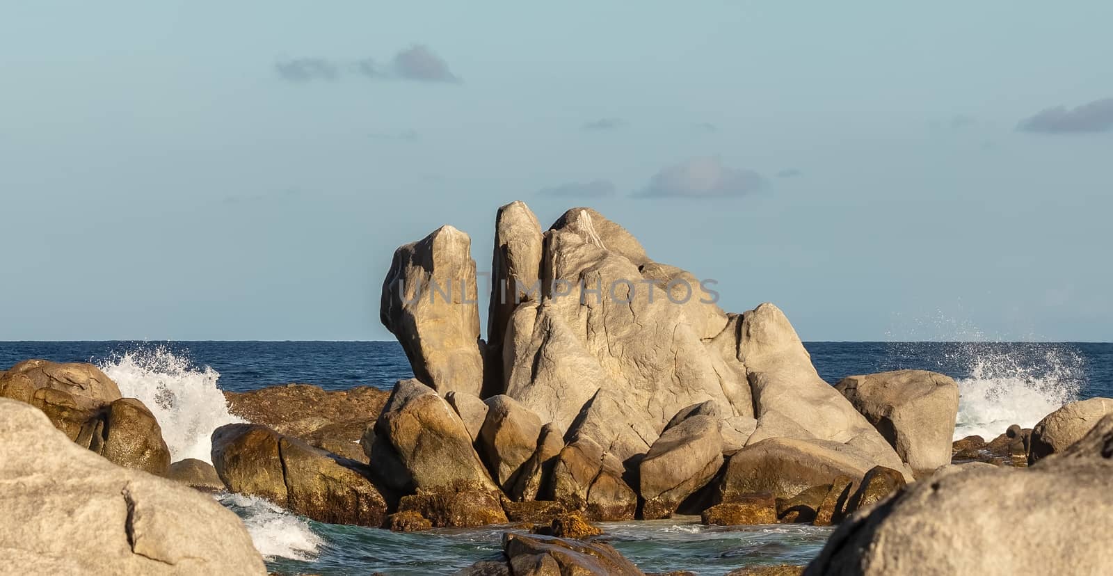Huge rock on a beach in Aruba with water splashing around it