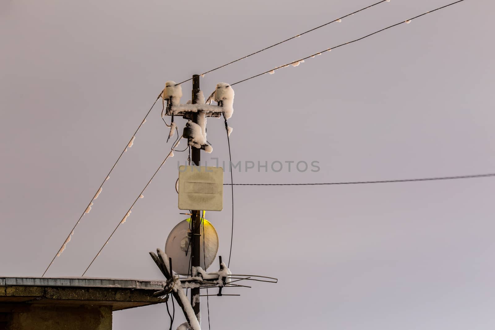 Frozen 5 GHz wireless antenna repeater pillar at winter night.
