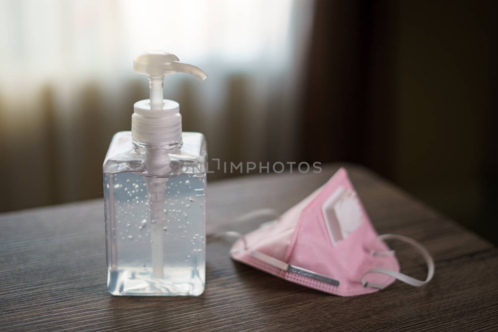 Antibacterial transparent hand sanitizer gel in a plastic bottle with surgical mask.