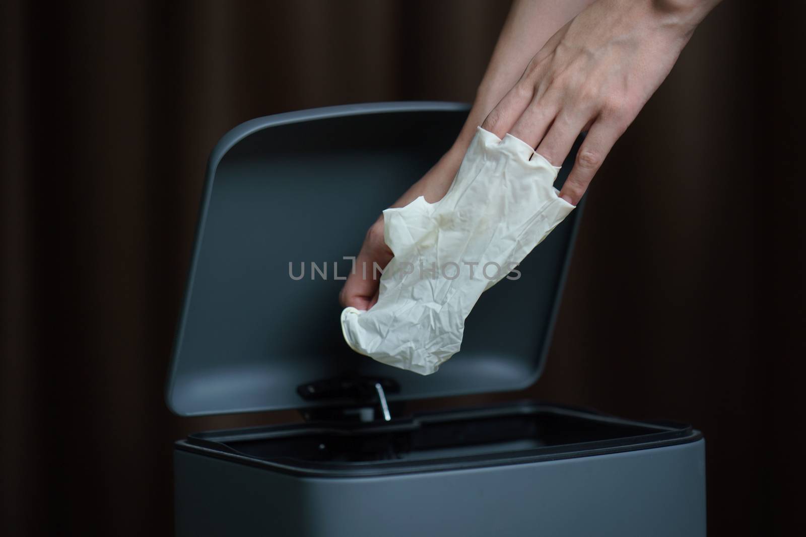 Hand putting used dirty surgical glove to a garbage bin. Mask protect dust and corona virus in trash.