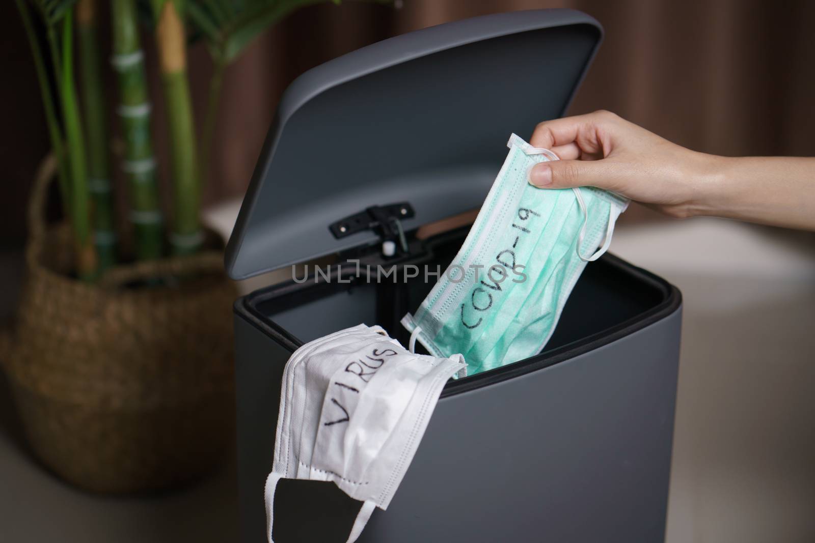 Hand putting used dirty surgical mask to a garbage bin. Mask protect dust and corona virus in trash.