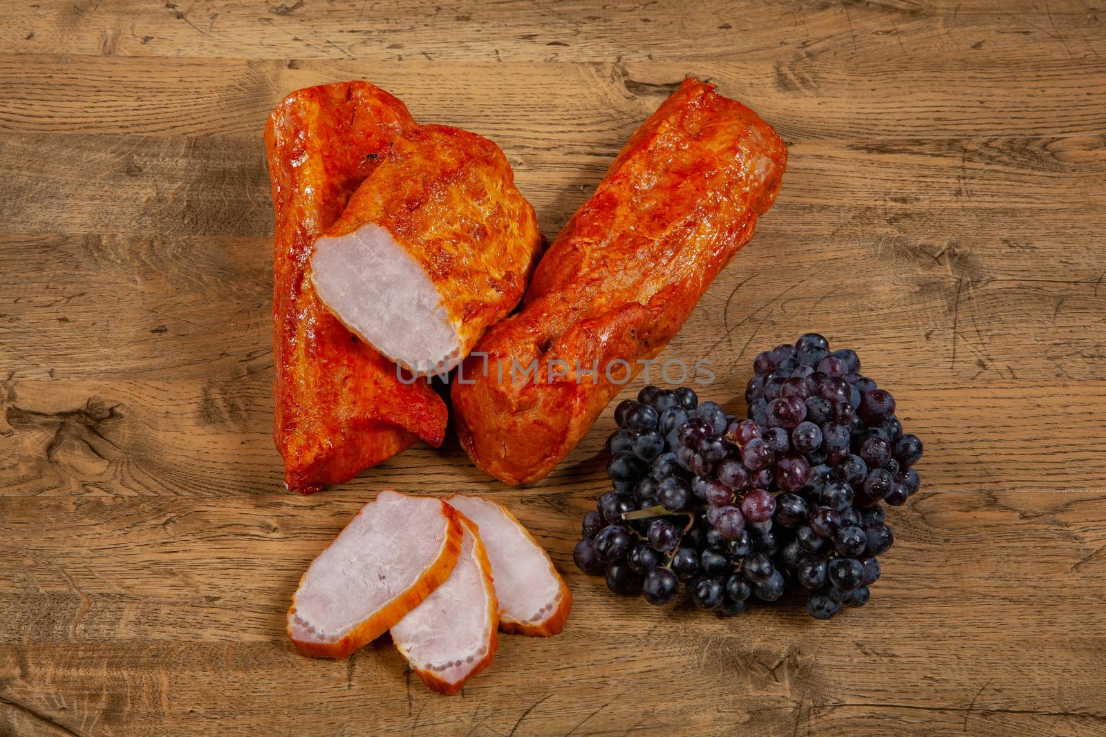 Ham sausage and grapevine on a wooden desk