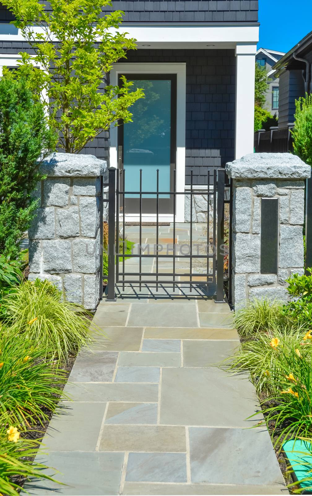 Stone tile paved pathway leading to the entrance door through metal grid gate