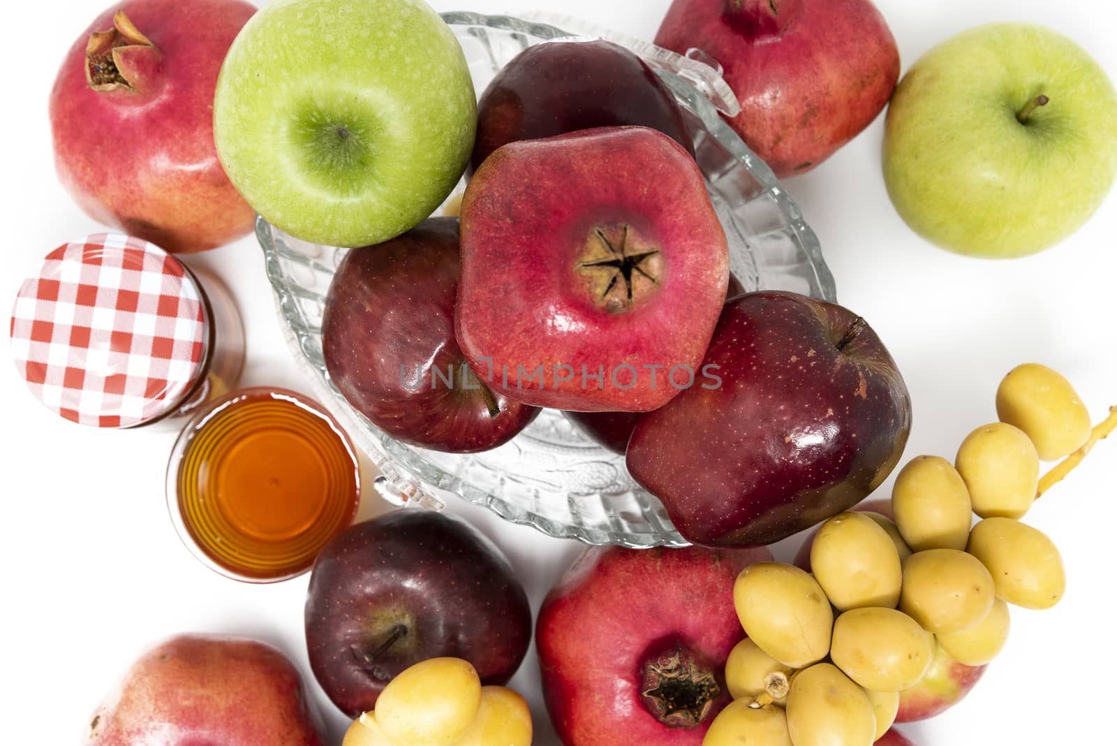 Rosh Hashanah, Jewish New Year, Traditional Symbols, Honey in a glass jar, Pomegranates, Dates, Red And Green Apples. Isolated On A White Background