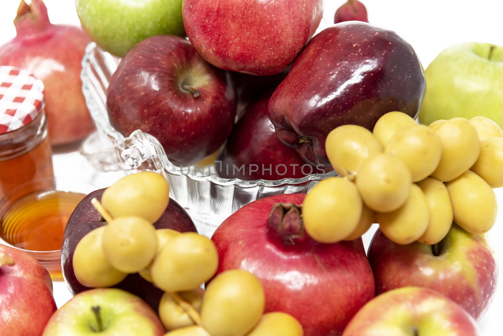 Rosh Hashanah, Jewish New Year, Traditional Symbols, Honey in a glass jar, Pomegranates, Dates, Red And Green Apples. Isolated On A White Background