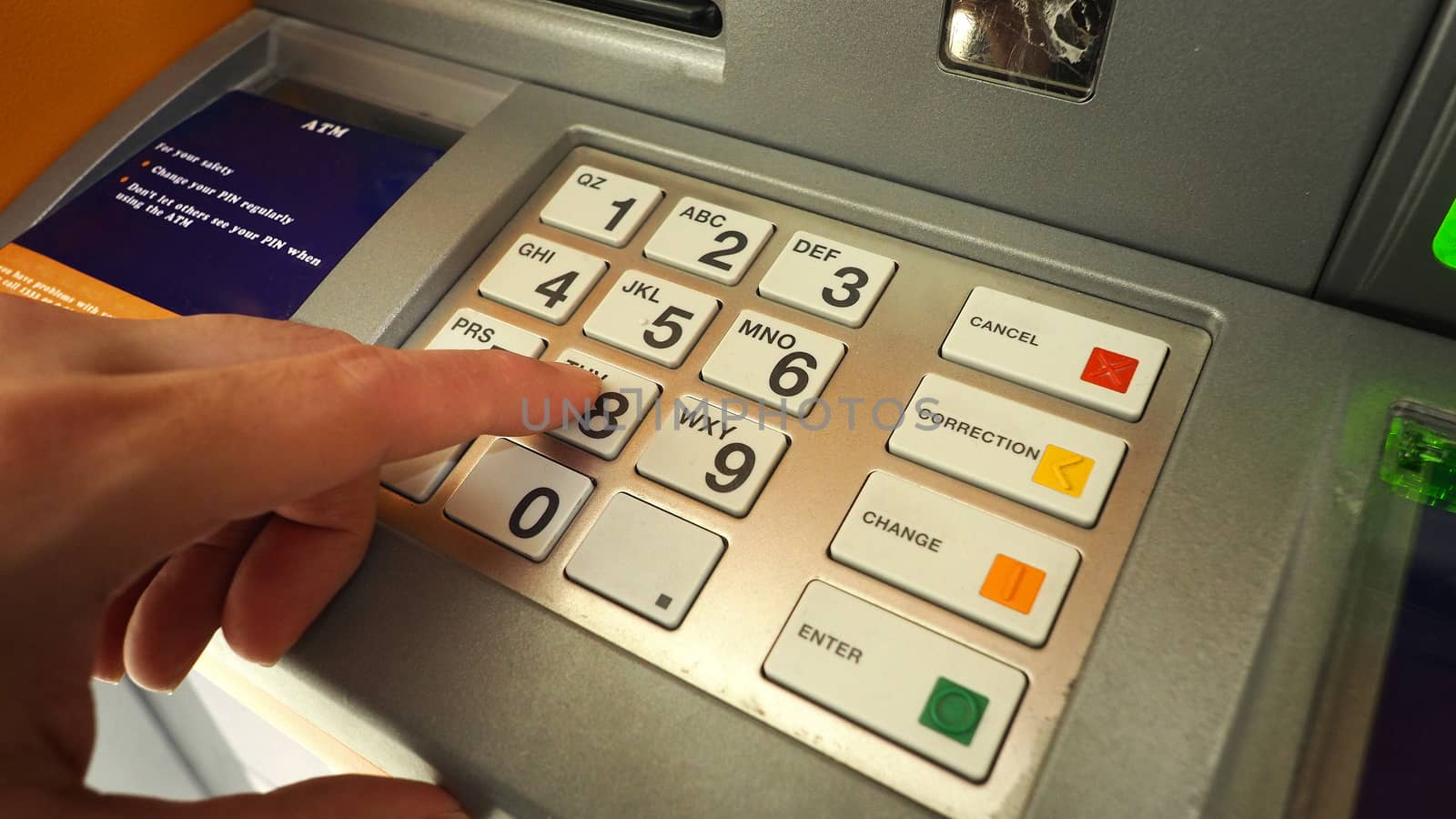 ATM machine and close-up man hand pushing on the pin number button to withdraw the money credit. 