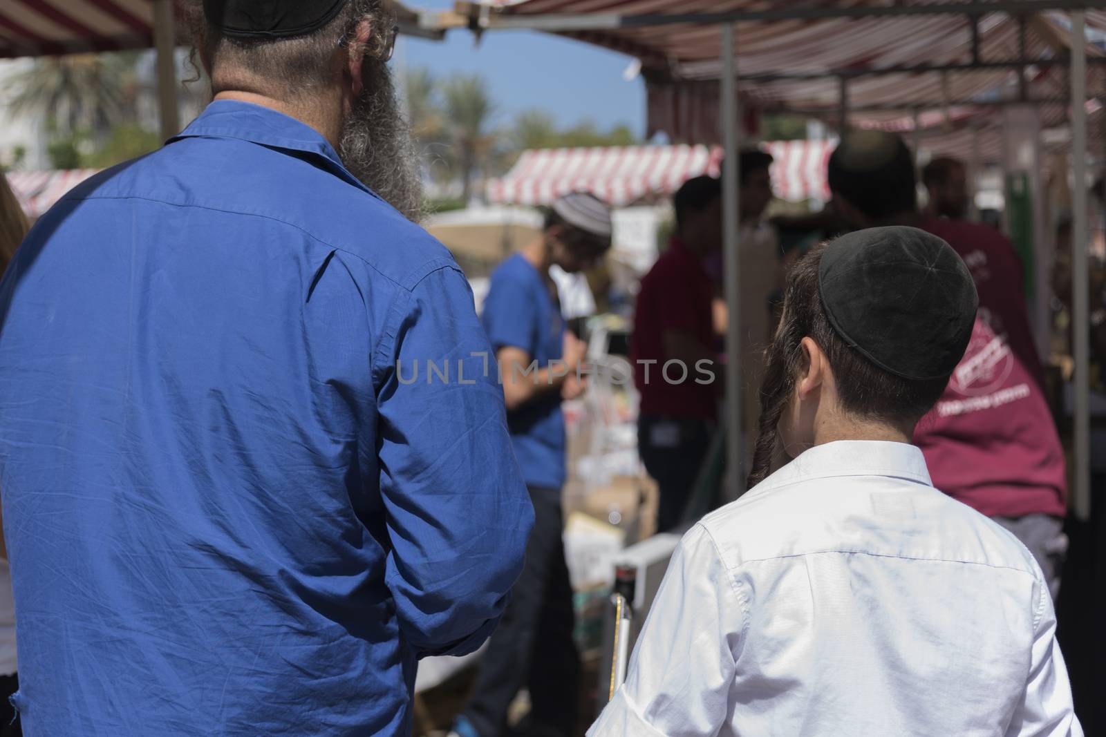 Jewish man with his son. Colorful sukkah decorations. Sukkot four species festival. Shimmering decorations for party.