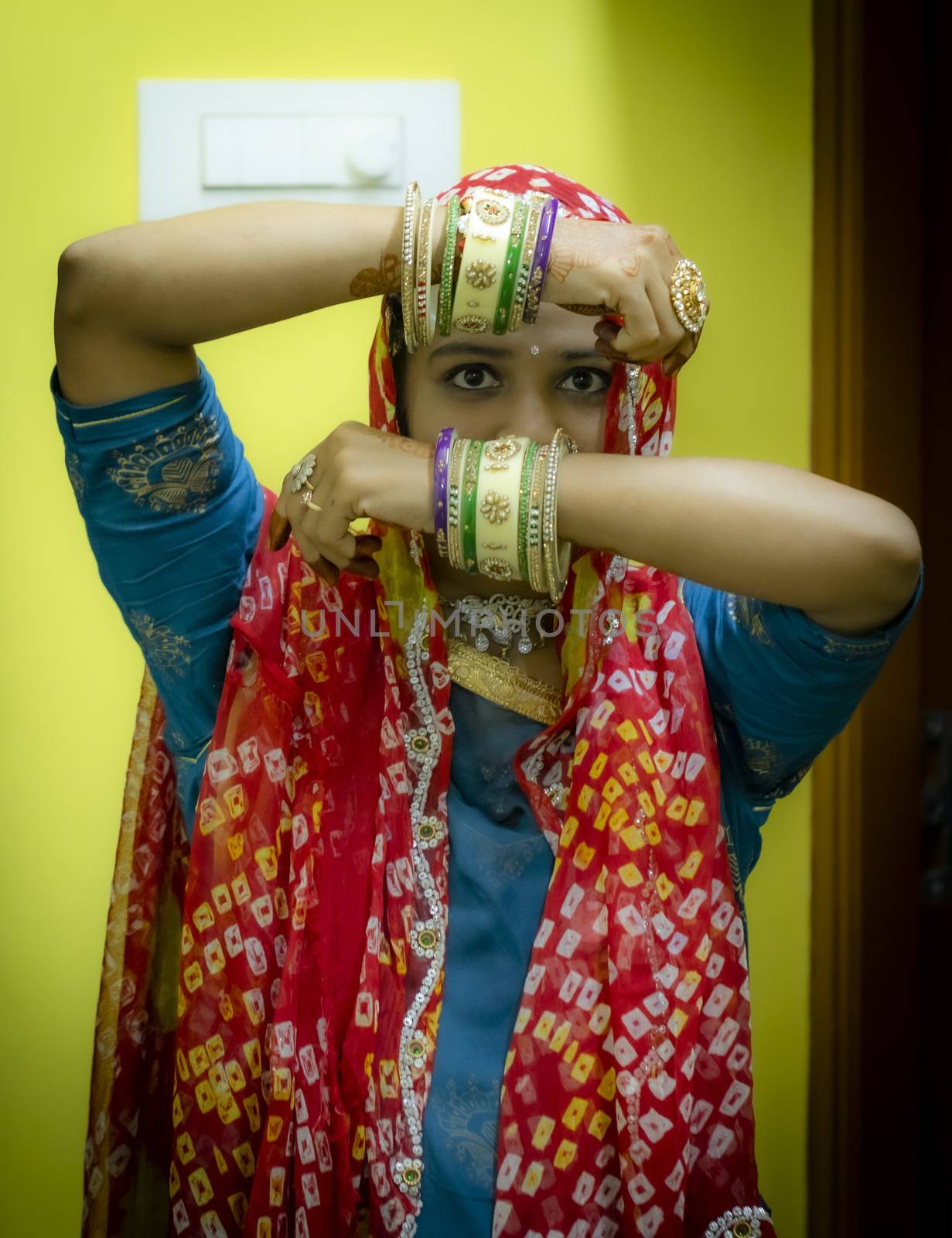 a woman sowing her face between his two hands with wearing colourful fancy cosmetic bangles, youth girls