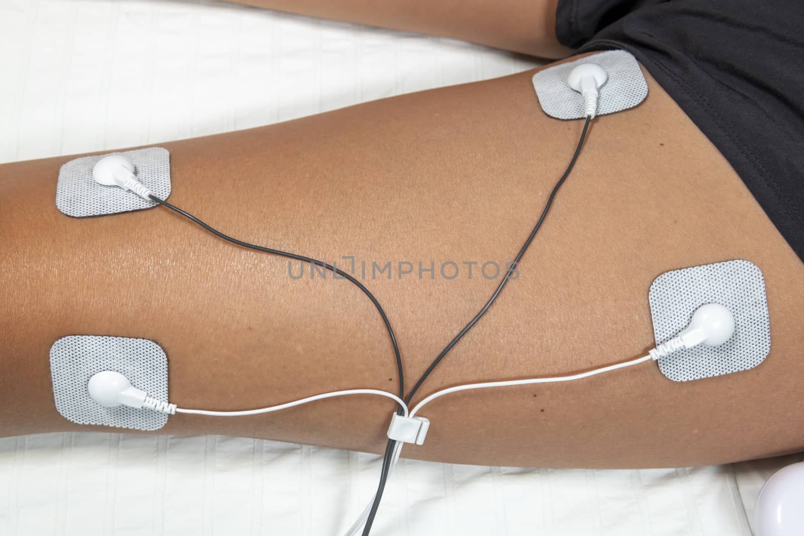 woman in the 40's using TENS (transcutaneous electrical nerve stimulation) and EMS (electronic muscle stimulation) Therapy machine at home on the muscle of one of her leg