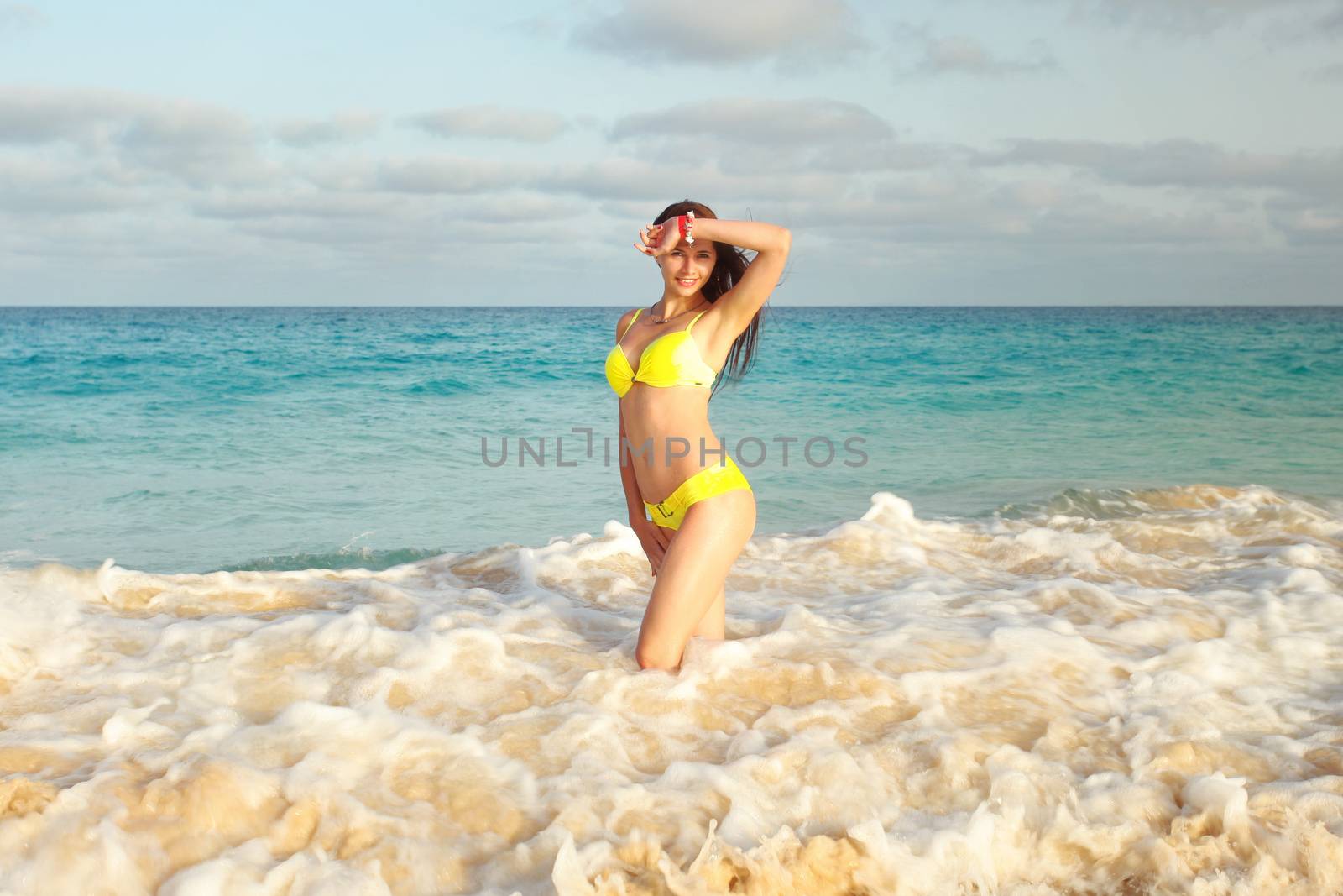 beatiful girl in yellow bikini on the beach, standing in the wat by Ivanko