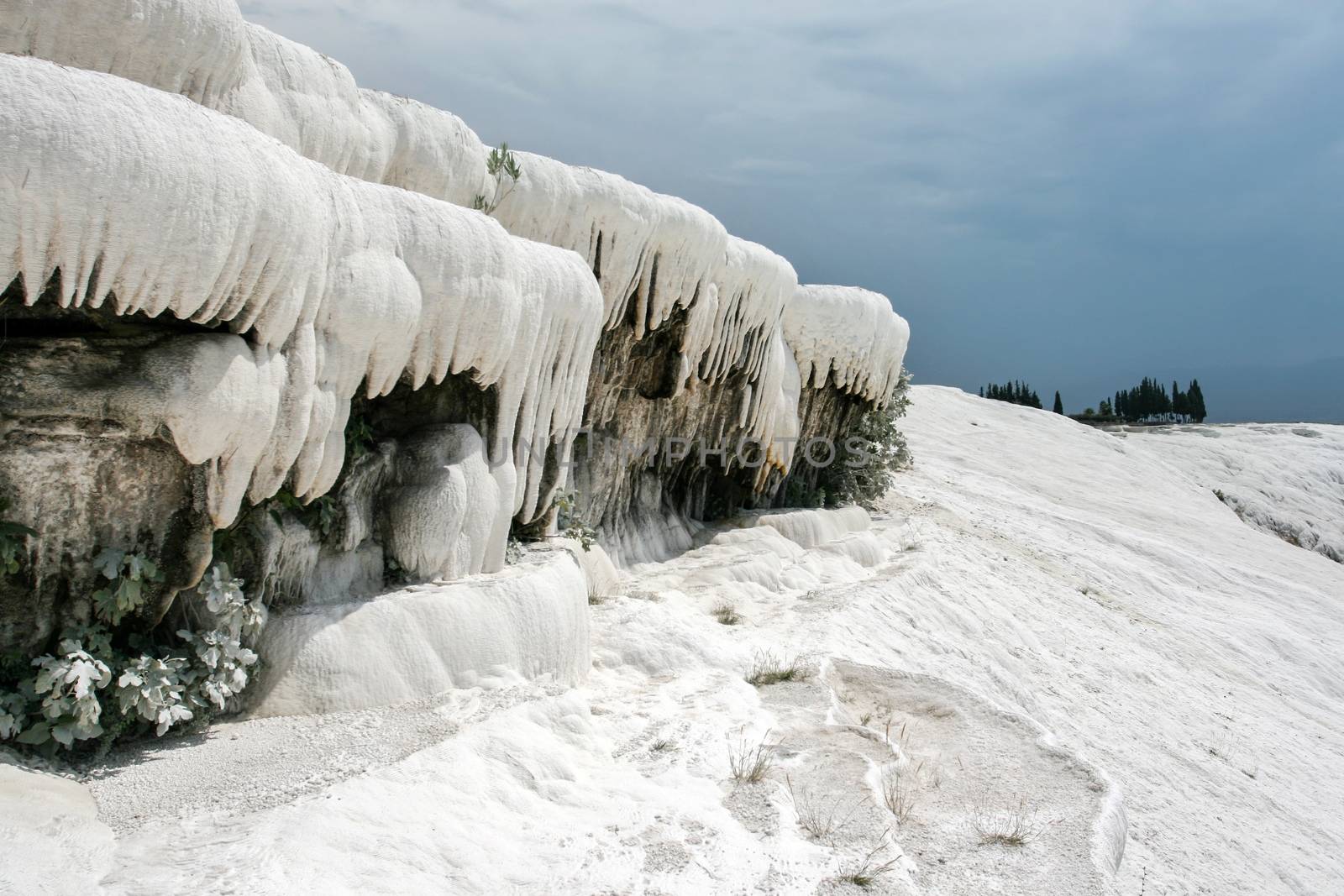 White travertine forming icicles / stalactites like objects, making landscape looks as snow covered winter scenery even tough it is hot summer day. Pamukkale (Cotton Castle), Hierapolis, Turkey.