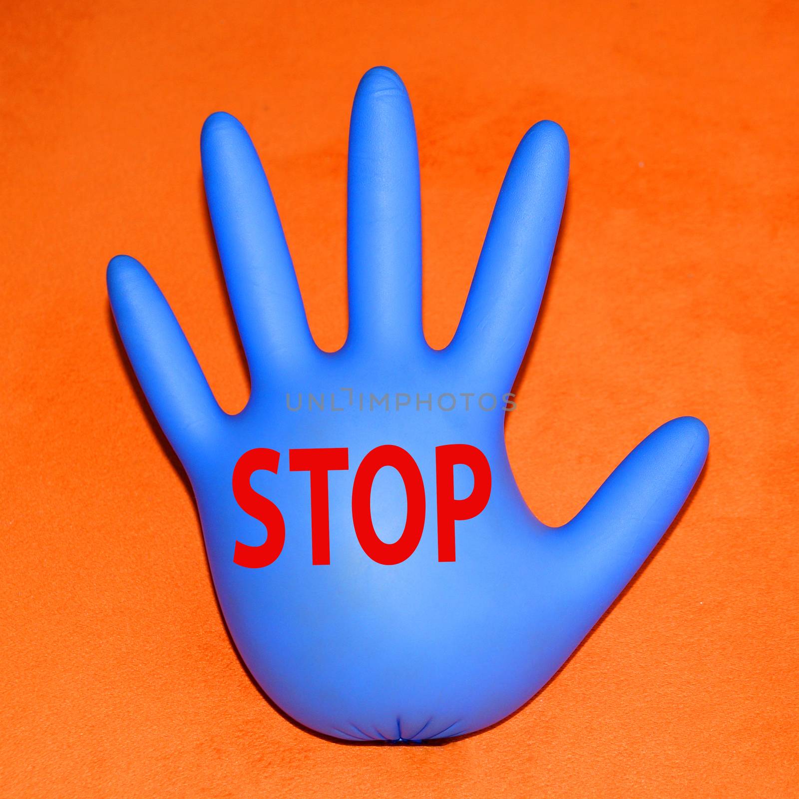 inflated rubber medical glove with stop sign on orange background, copy space, square photo