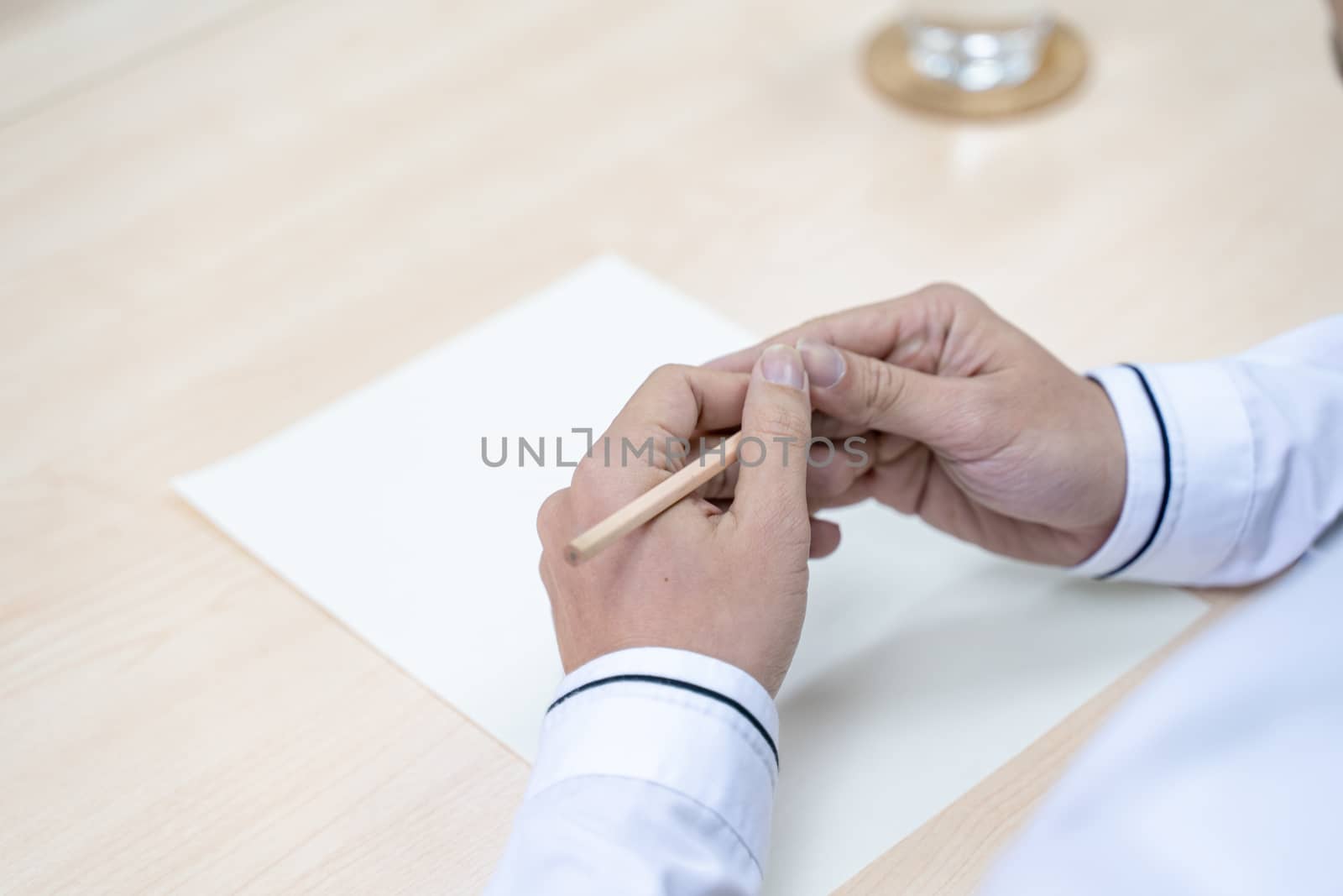 Hand image of a businessman holding a pencil on white paper, concept of working in the office.