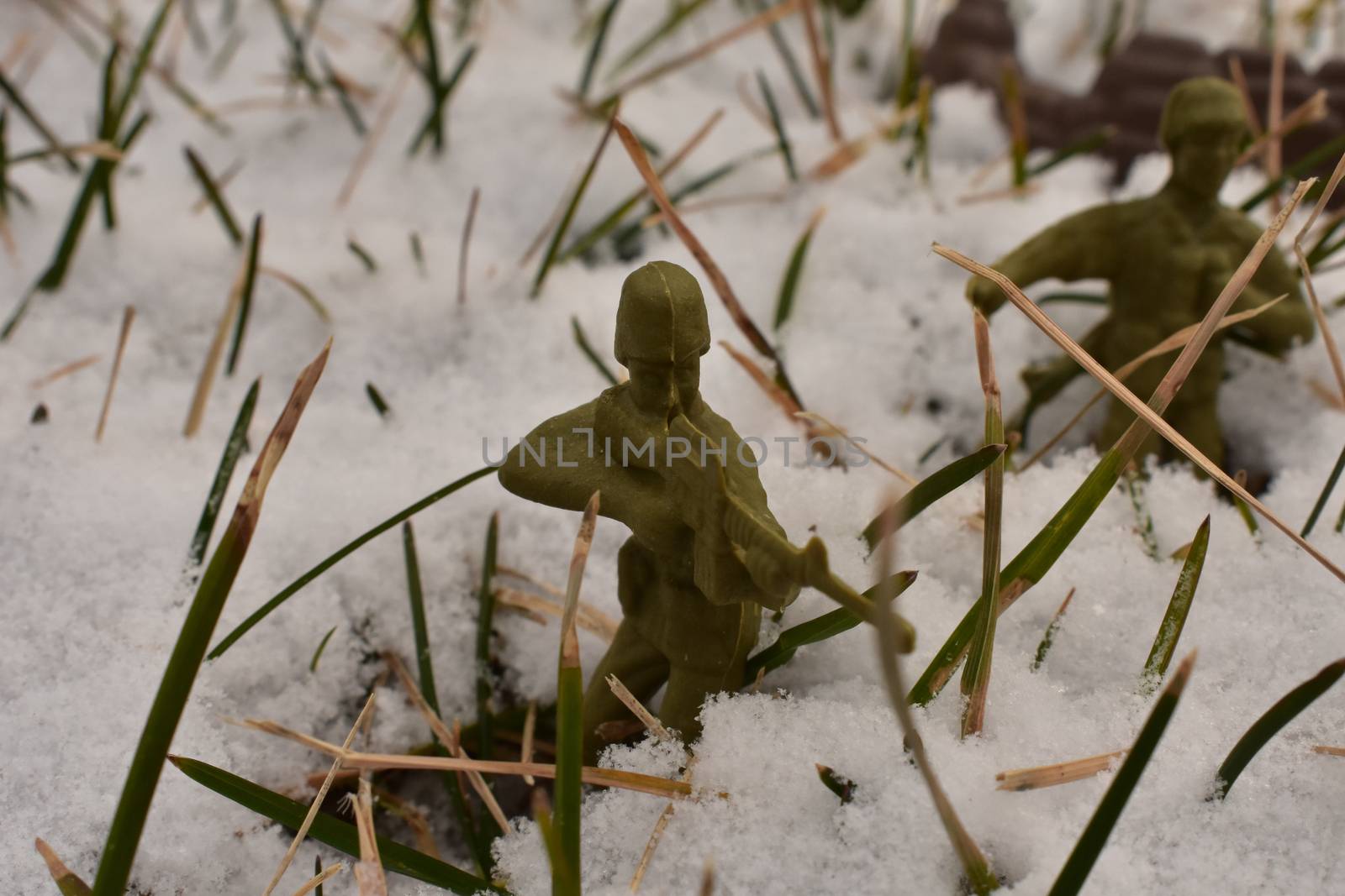 A Toy Soldier Taking Aim and Ready to Fight in a Snowy Field by bju12290