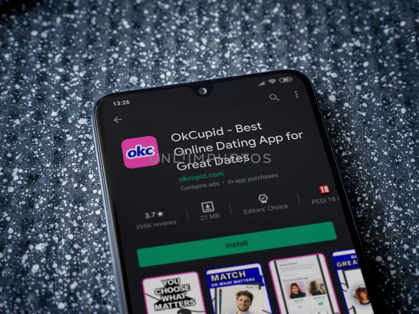 Lod, Israel - July 8, 2020: OkCupid app play store page on the display of a black mobile smartphone on a metallic background. Close up top view flat lay.